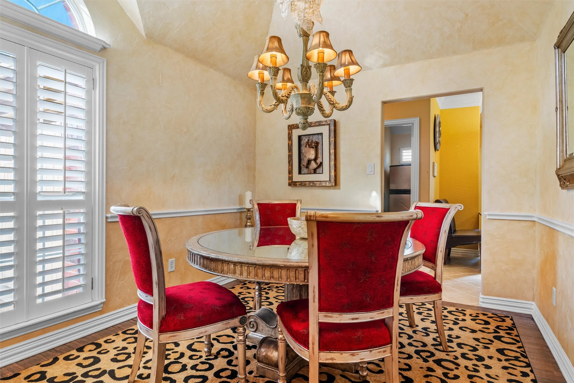 Arched ceiling featuring a chandelier, window with plantation shutters, teak wood flooring