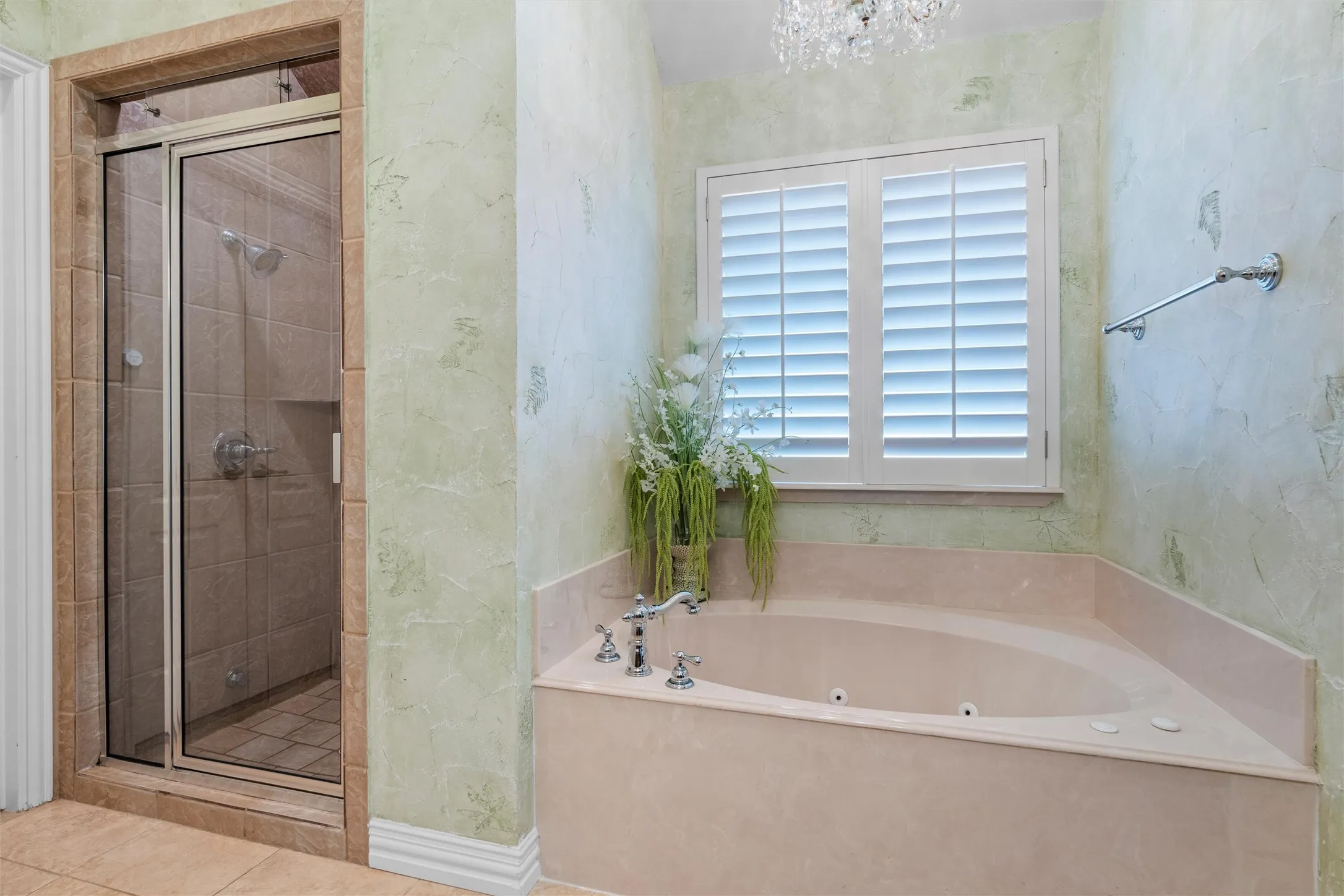 Primary Bath tiled shower with glass enclosure, jetted tub and window with plantation shutters