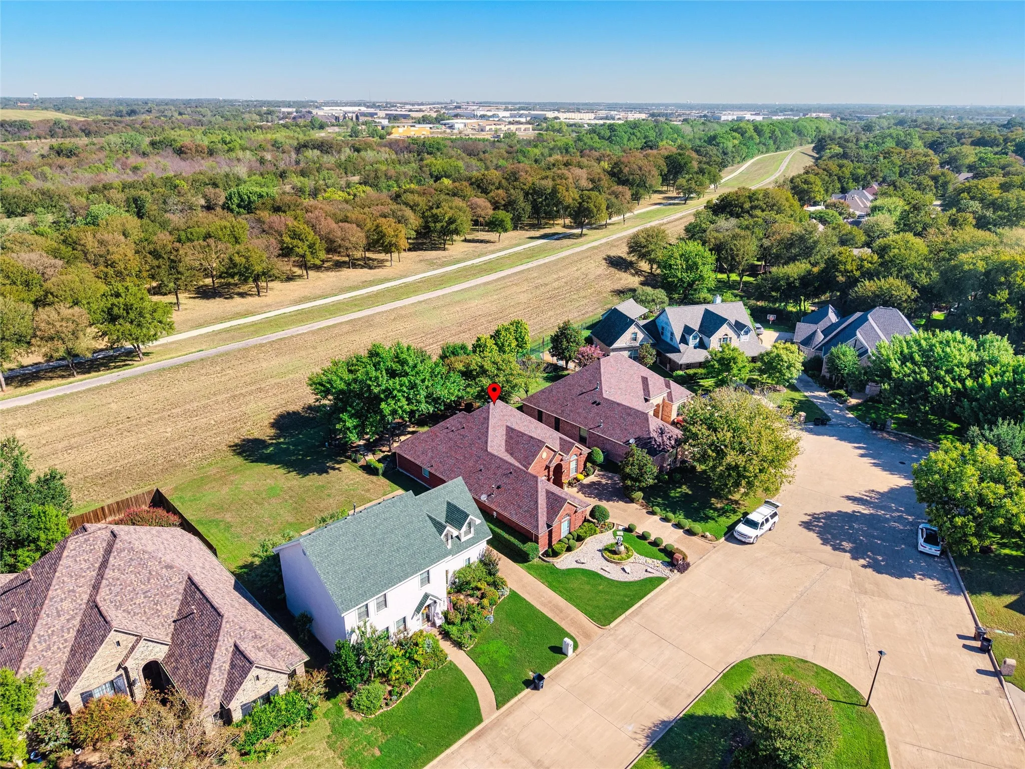 Aerial perspective showcasing the residential street, mature trees, and expansive green spaces