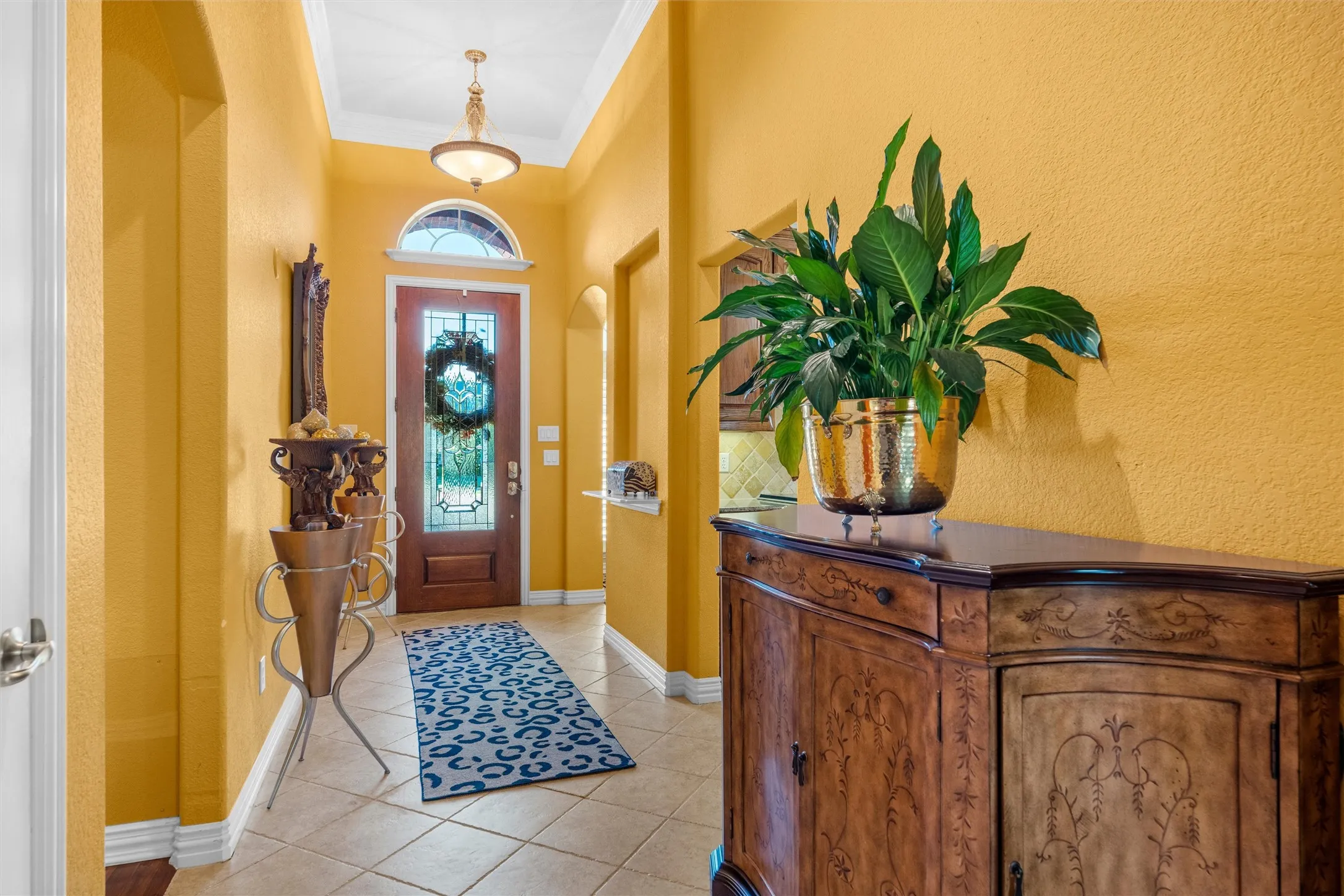 Arched entryway with a wood-paneled door, decorative glass inserts, and an overhead transom window