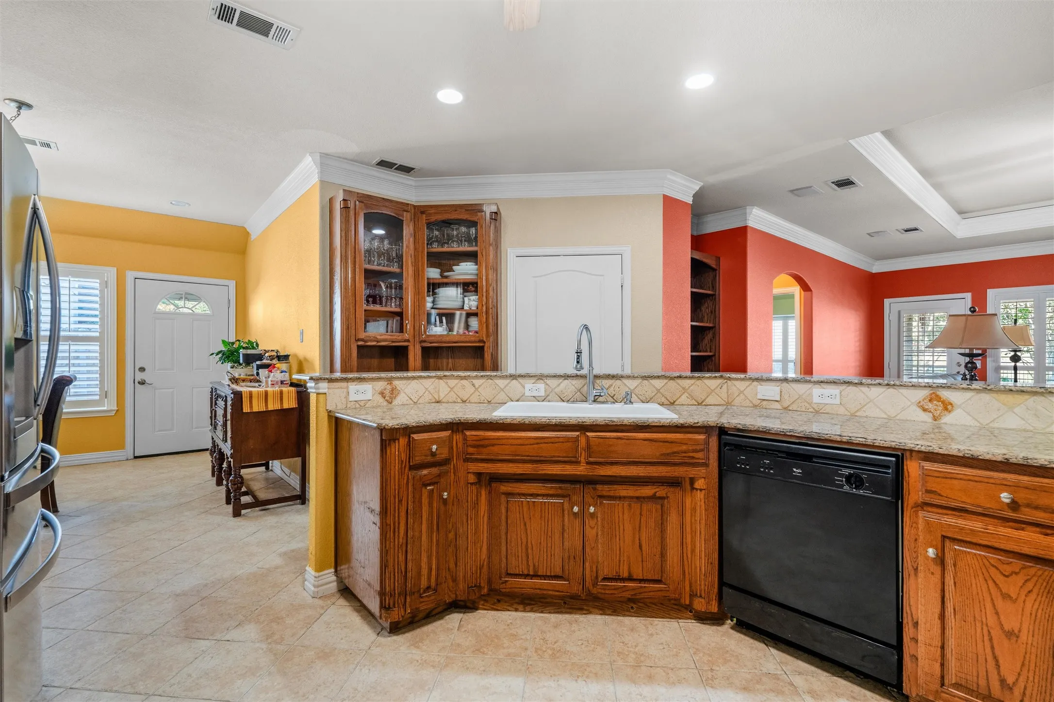 Kitchen featuring wood cabinetry, a built-in corner china cabinet with glass doors, a tile backsplash, and a built-in dishwasher