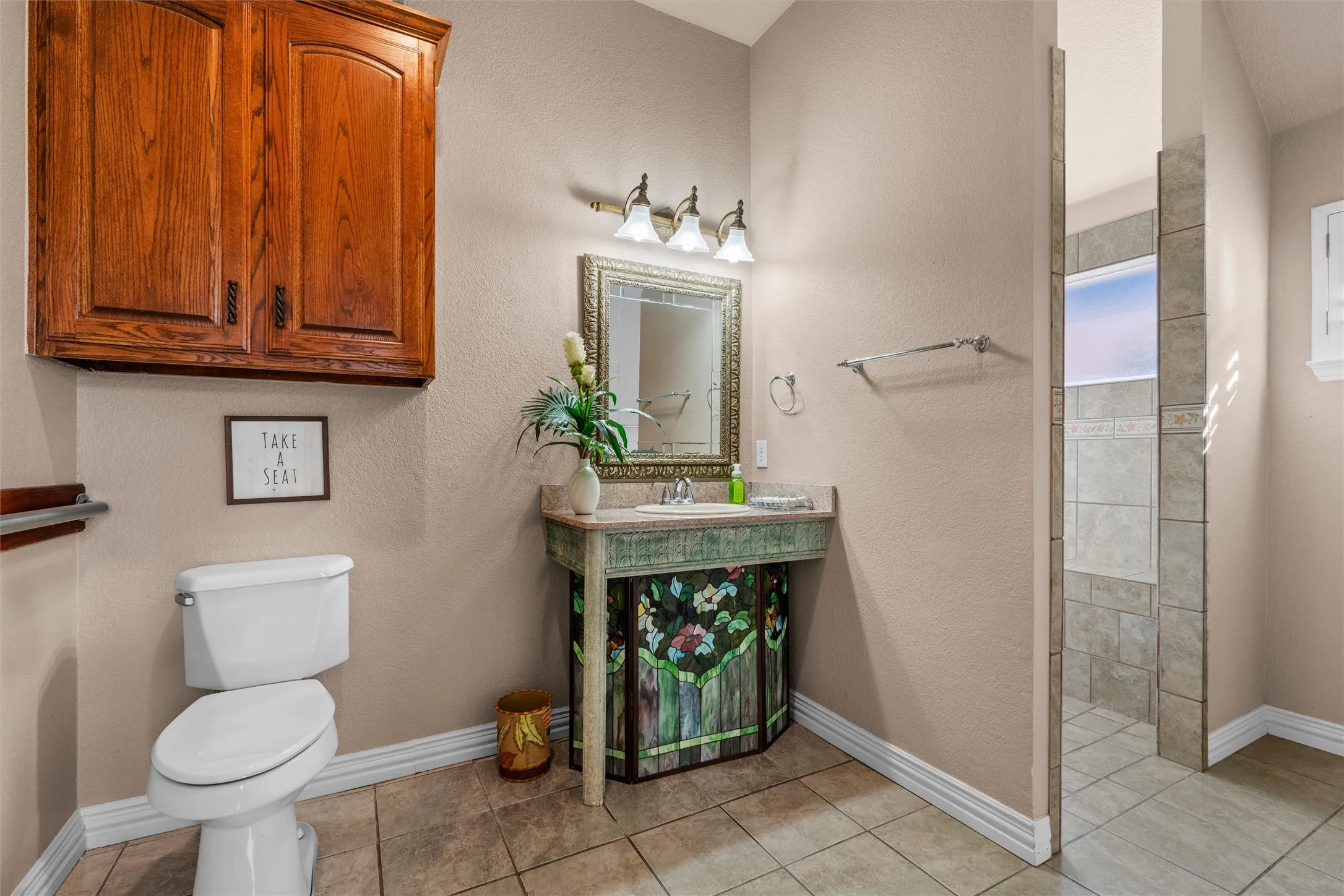 2nd Full bath walk-in shower with tiled surround, wood-finish wall-mounted cabinetry, and a vanity with an integrated sink