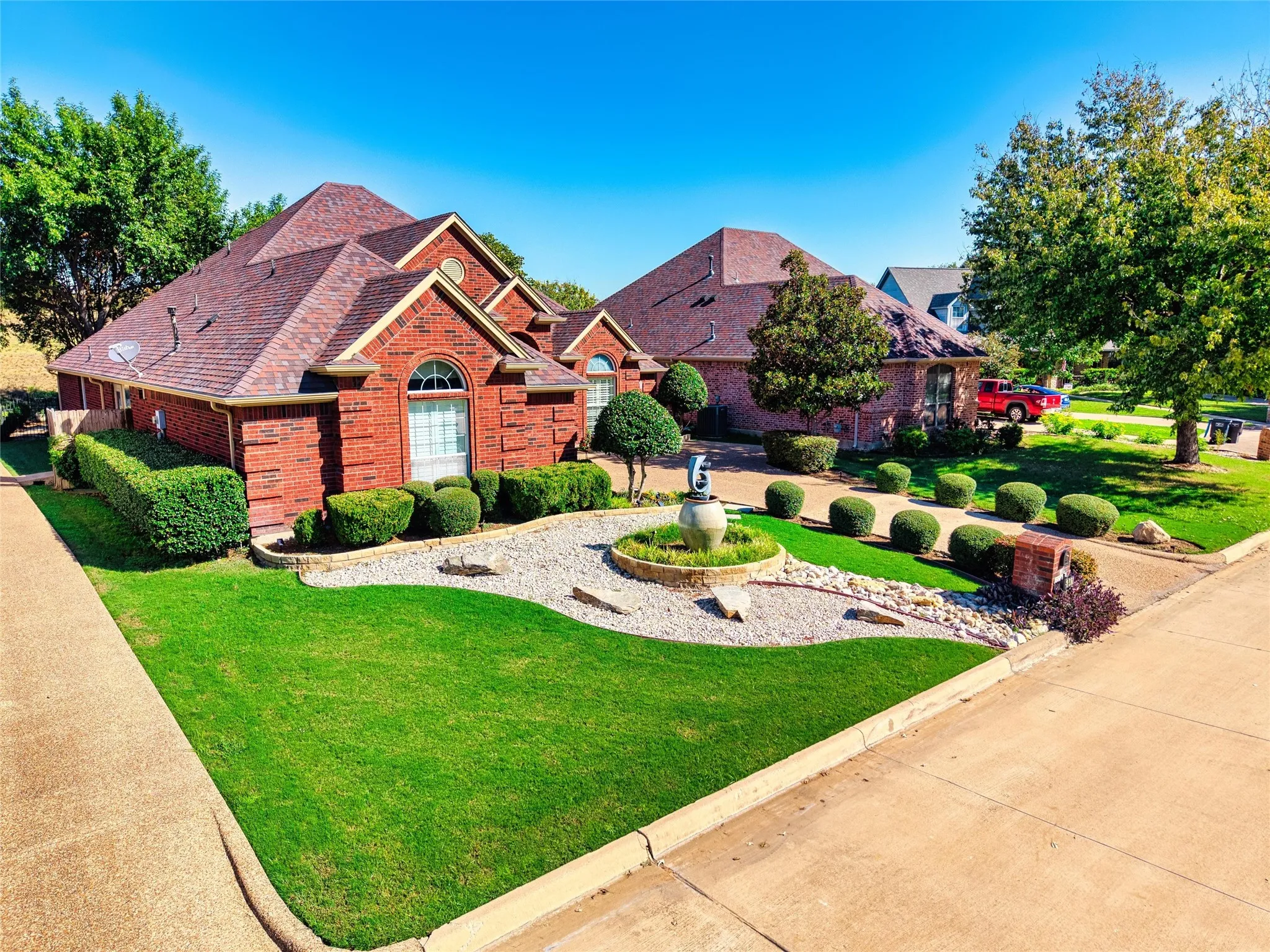 Brick exterior with an arched window, a gabled roofline, and a manicured lawn
