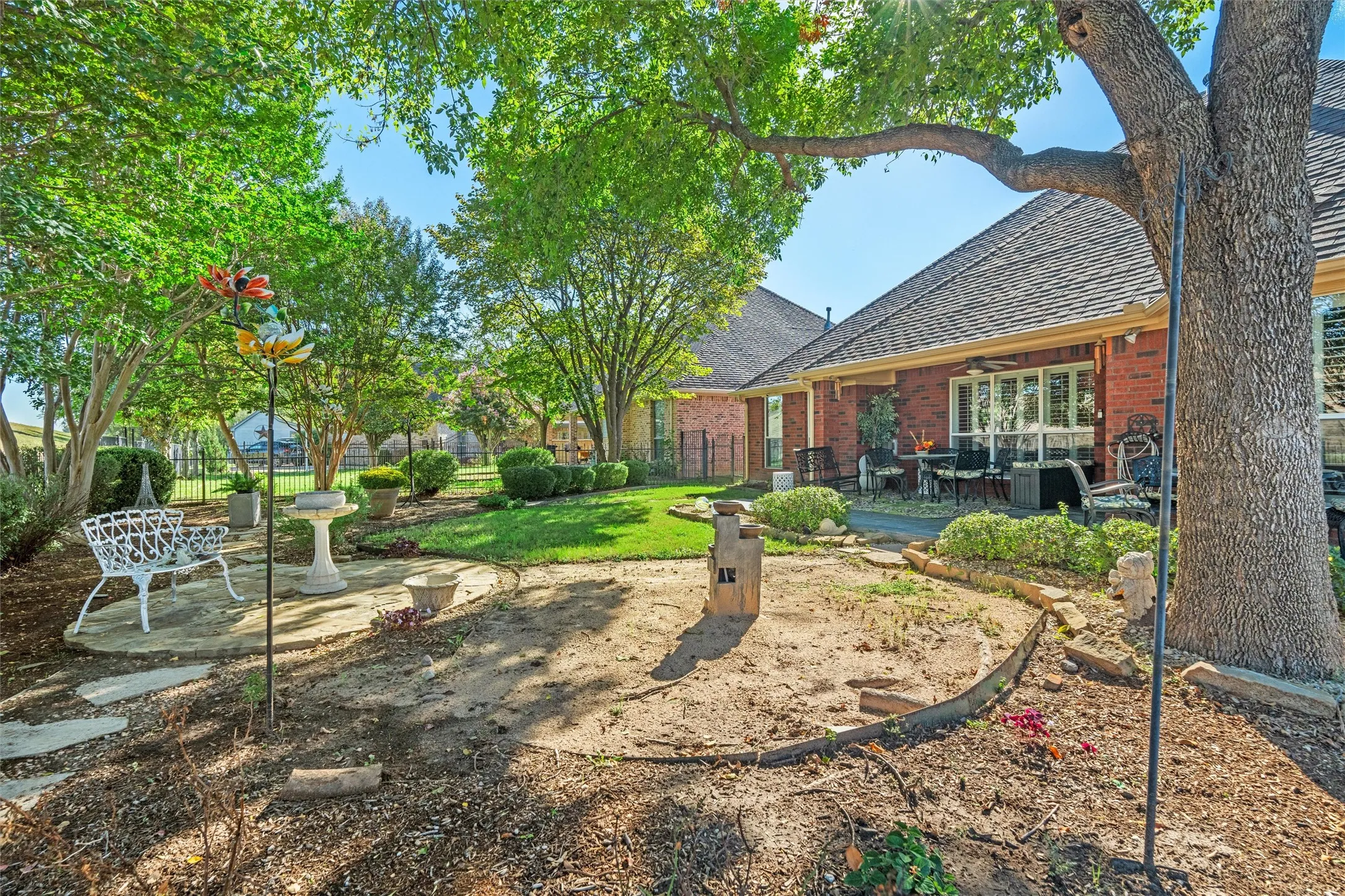 Expansive backyard featuring mature trees, a manicured lawn, and a stone patio