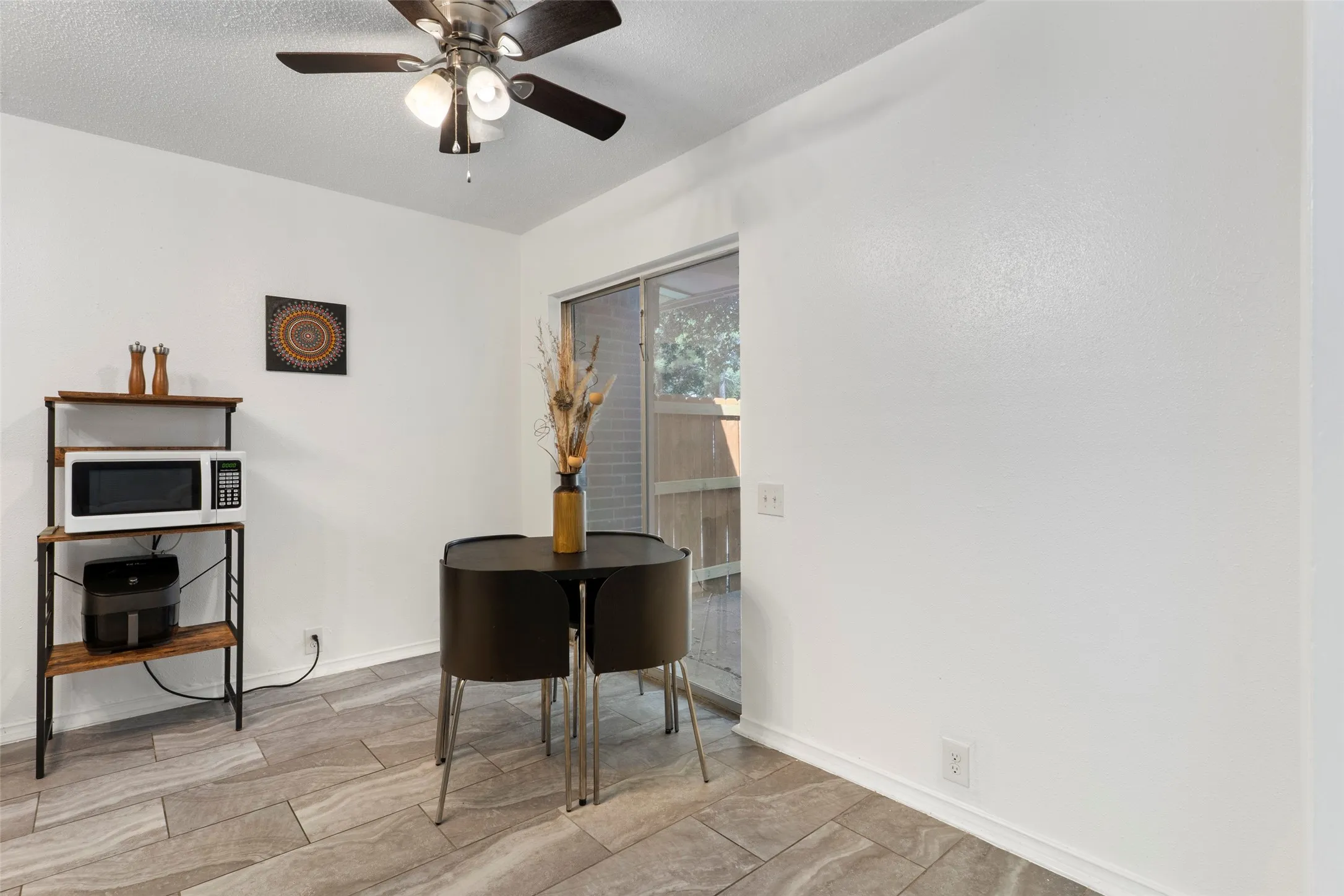 Porcelain tile flooring, ceiling fan with integrated lighting, white walls, and a sliding glass door