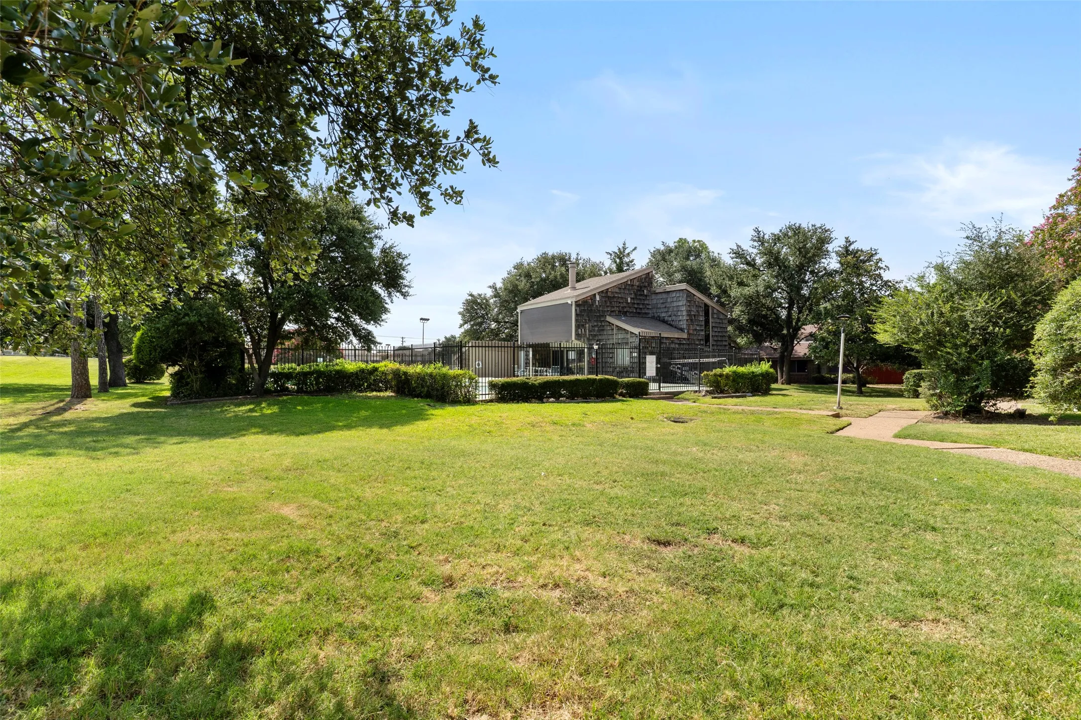 Expansive lawn area with mature trees and a paved walkway