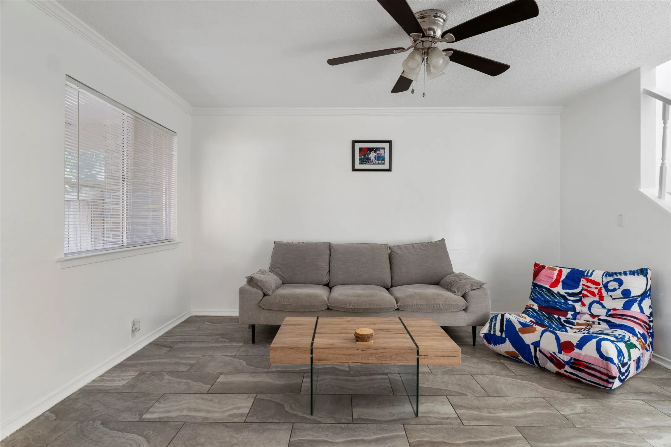 Spacious room featuring durable tile flooring, crown molding, and a ceiling fan with light fixture