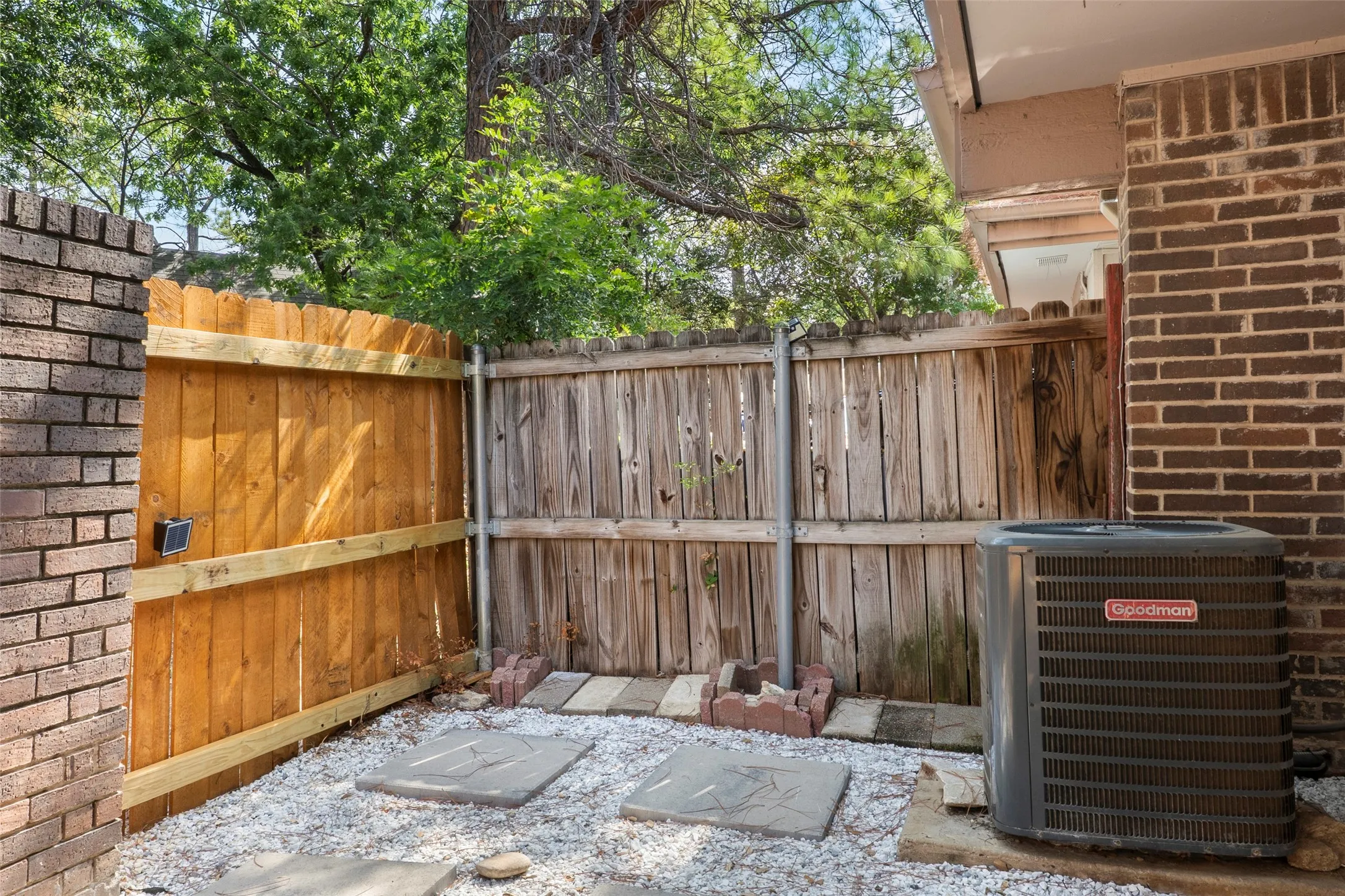 Brick exterior with a Goodman HVAC unit and a wood privacy fence