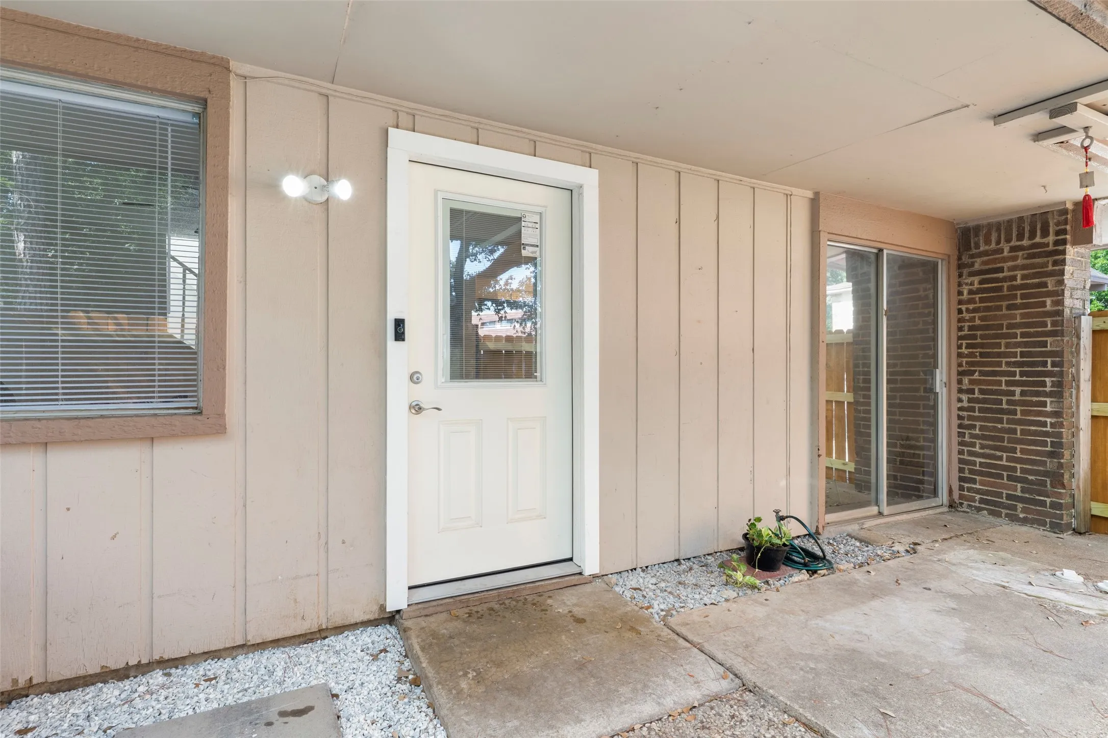 Covered patio featuring concrete flooring, a white paneled door with glass insert, and a sliding glass door