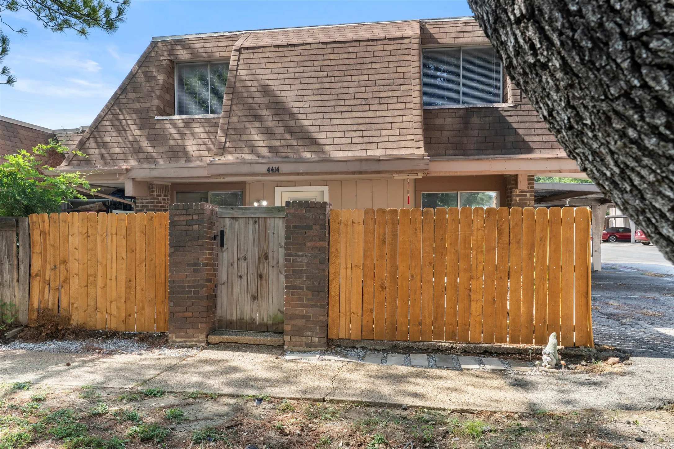 Welcoming front entry featuring wooden privacy gates with brick and stone detailing