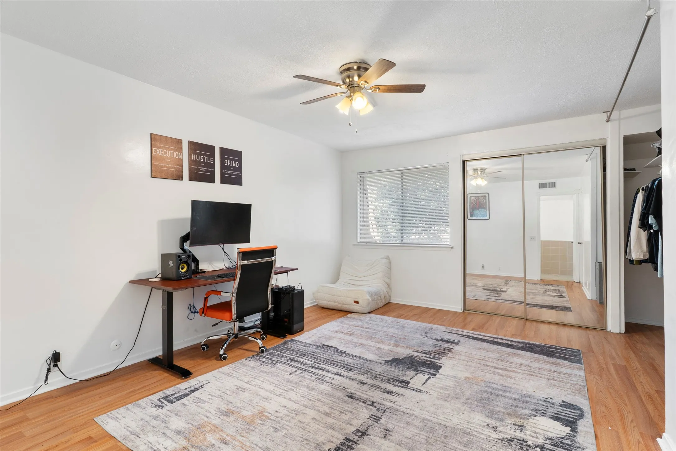 Wood-finish flooring throughout, ceiling fan with light fixture, mirrored sliding closet doors, and single window