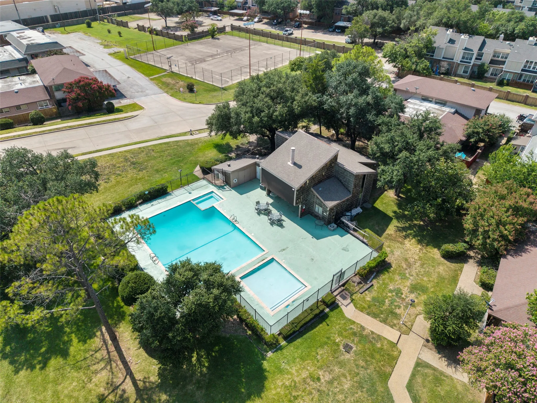 Resort-style saltwater swimming pool with sun deck and shallow lounging area, surrounded by mature landscaping and lush lawn