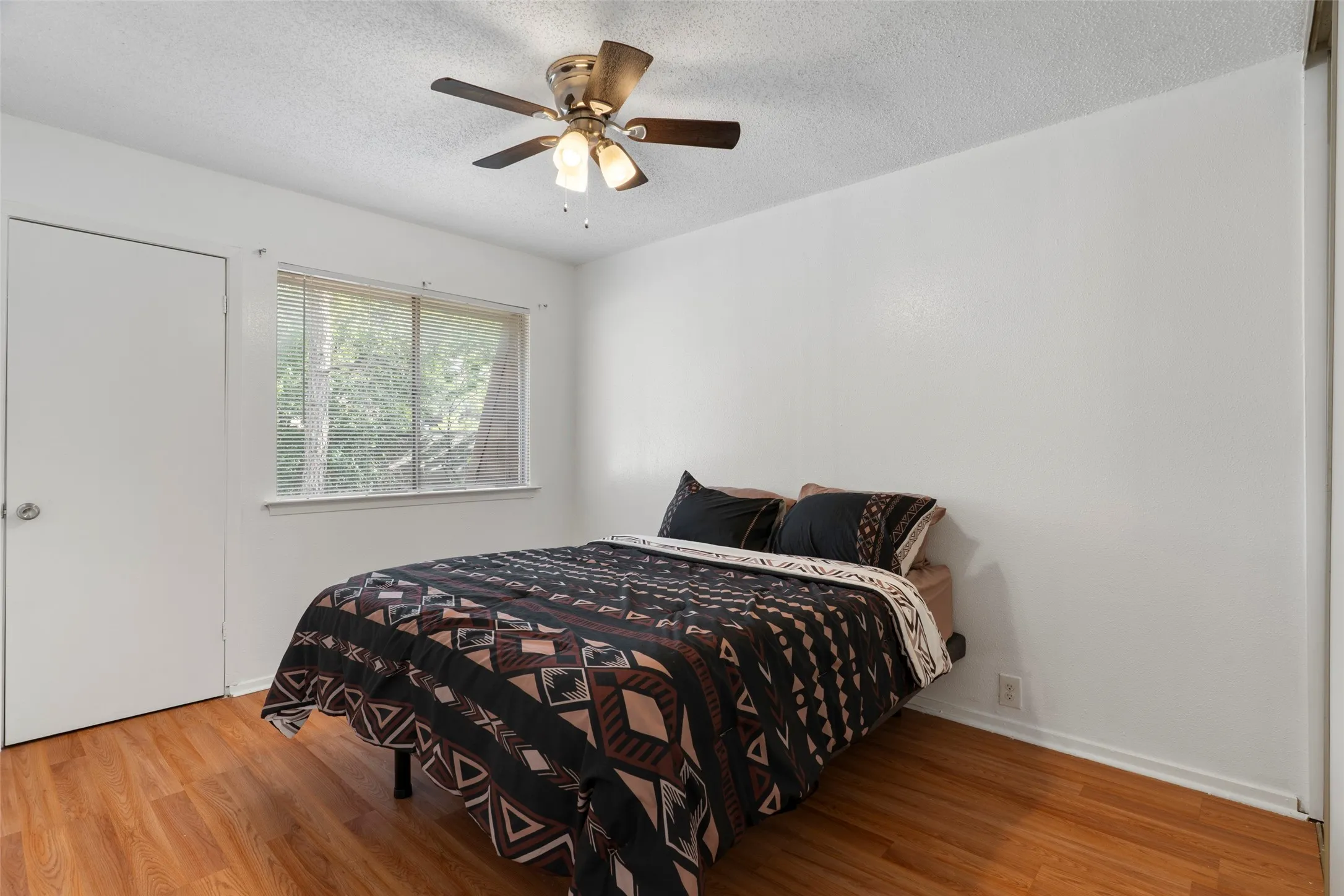 Wood-finish flooring, white walls, and a window with blinds