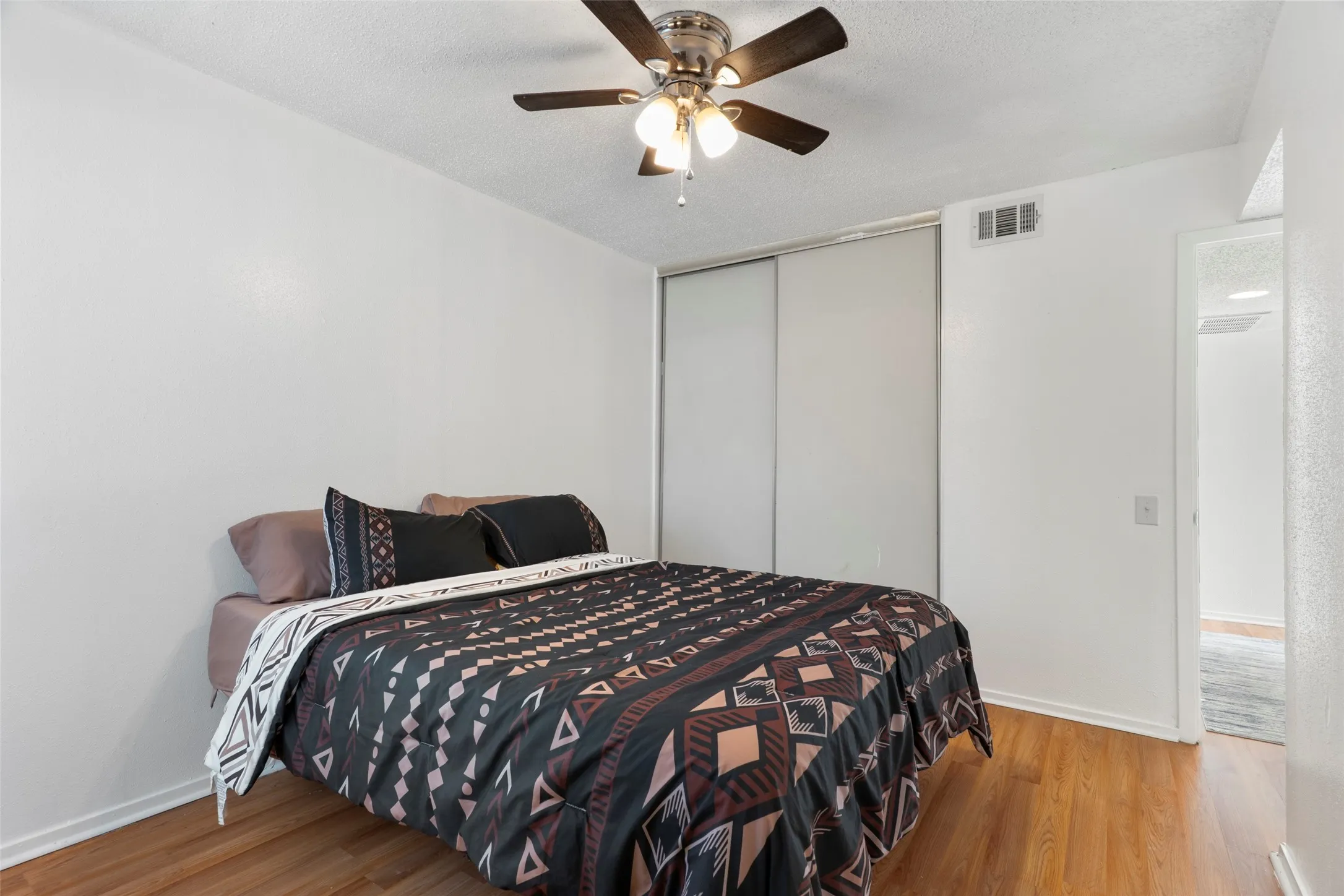 Wood-finish flooring with a ceiling fan and overhead lighting