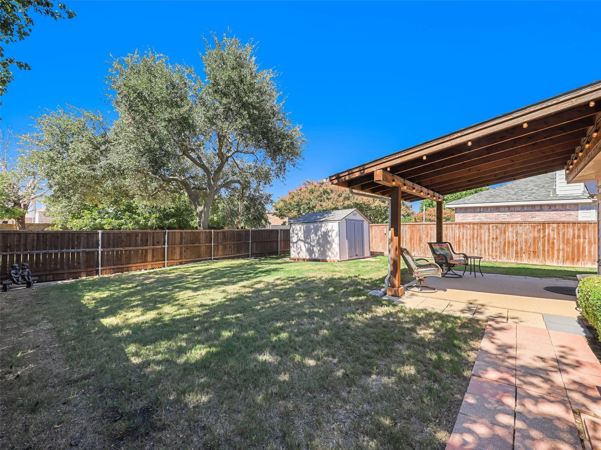 Large backyard with wood covered patio and storage shed