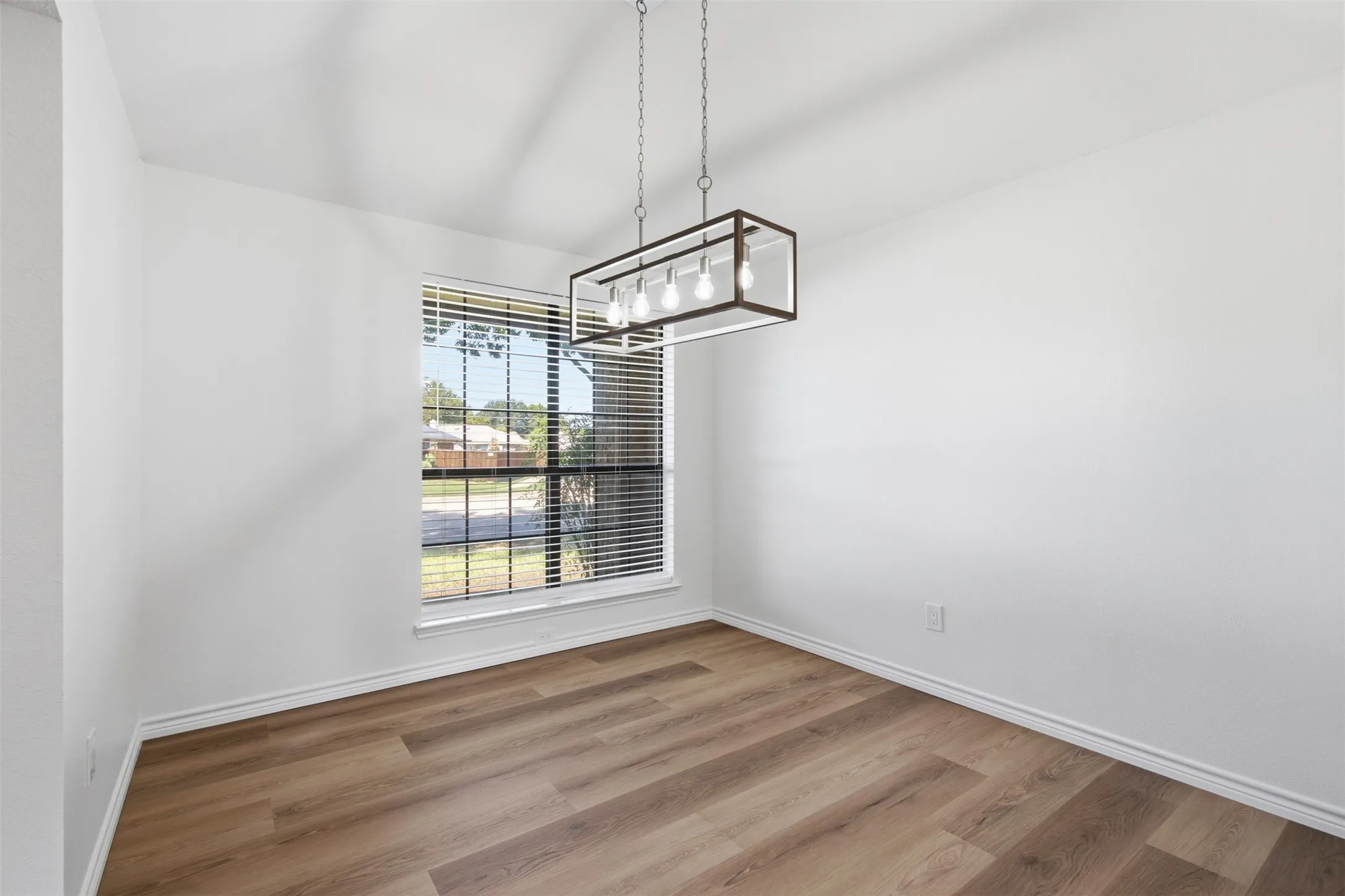 Recessed window with horizontal blinds, wood-finish flooring, and a modern rectangular chandelier
