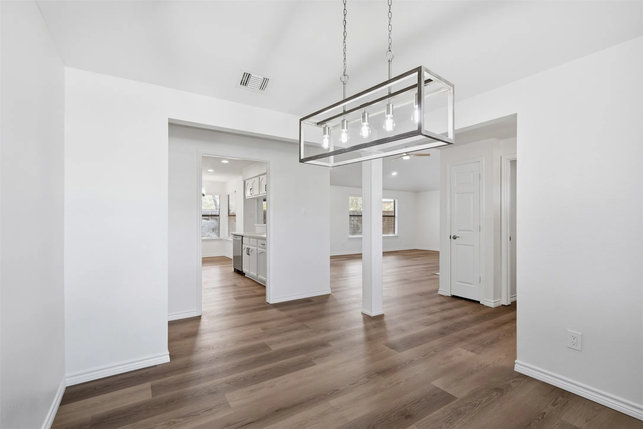 Wood-finish flooring throughout, with a linear chandelier, recessed lighting, and white interior doors