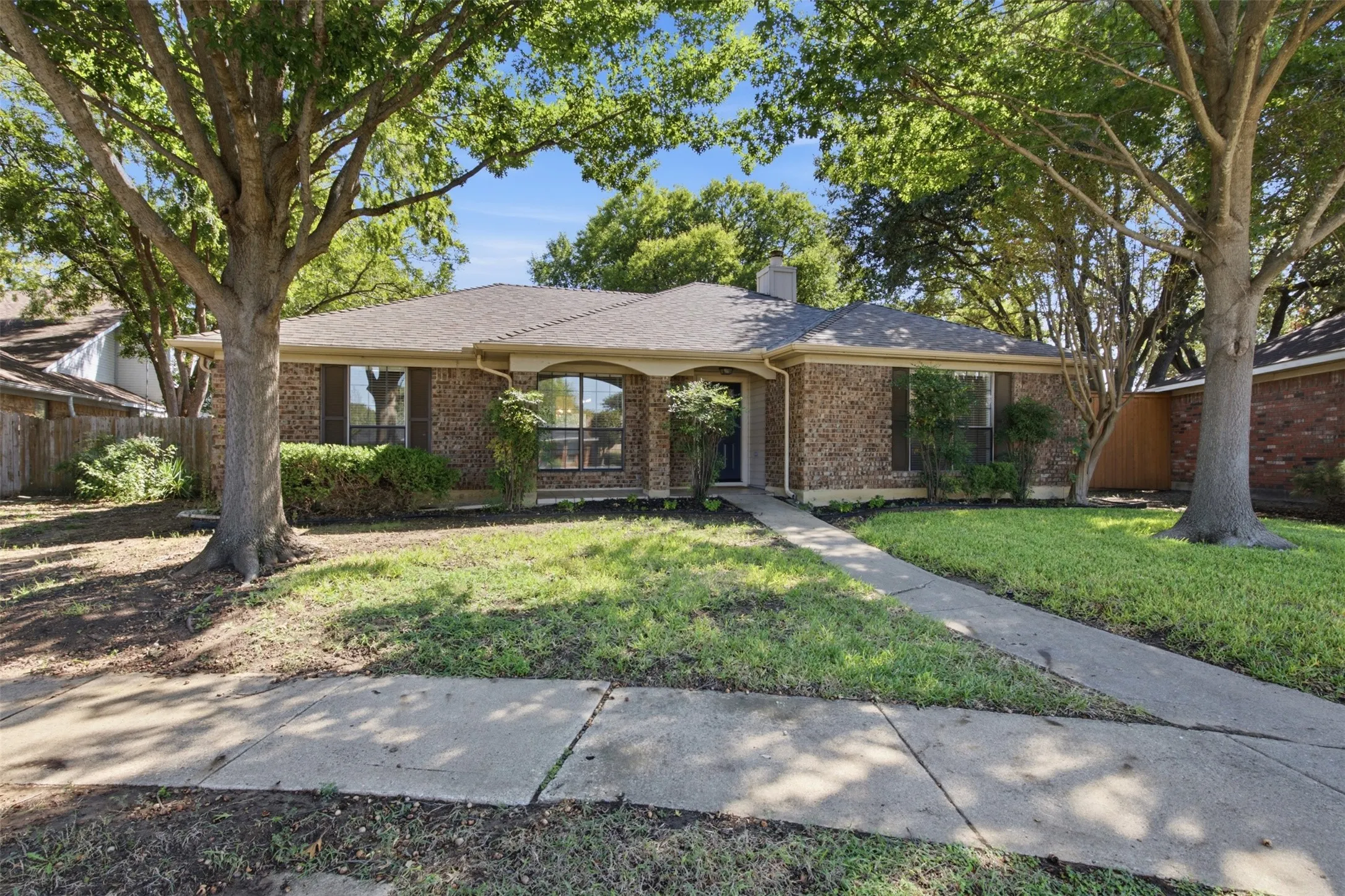 Brick exterior with a gabled roof and mature trees framing the property
