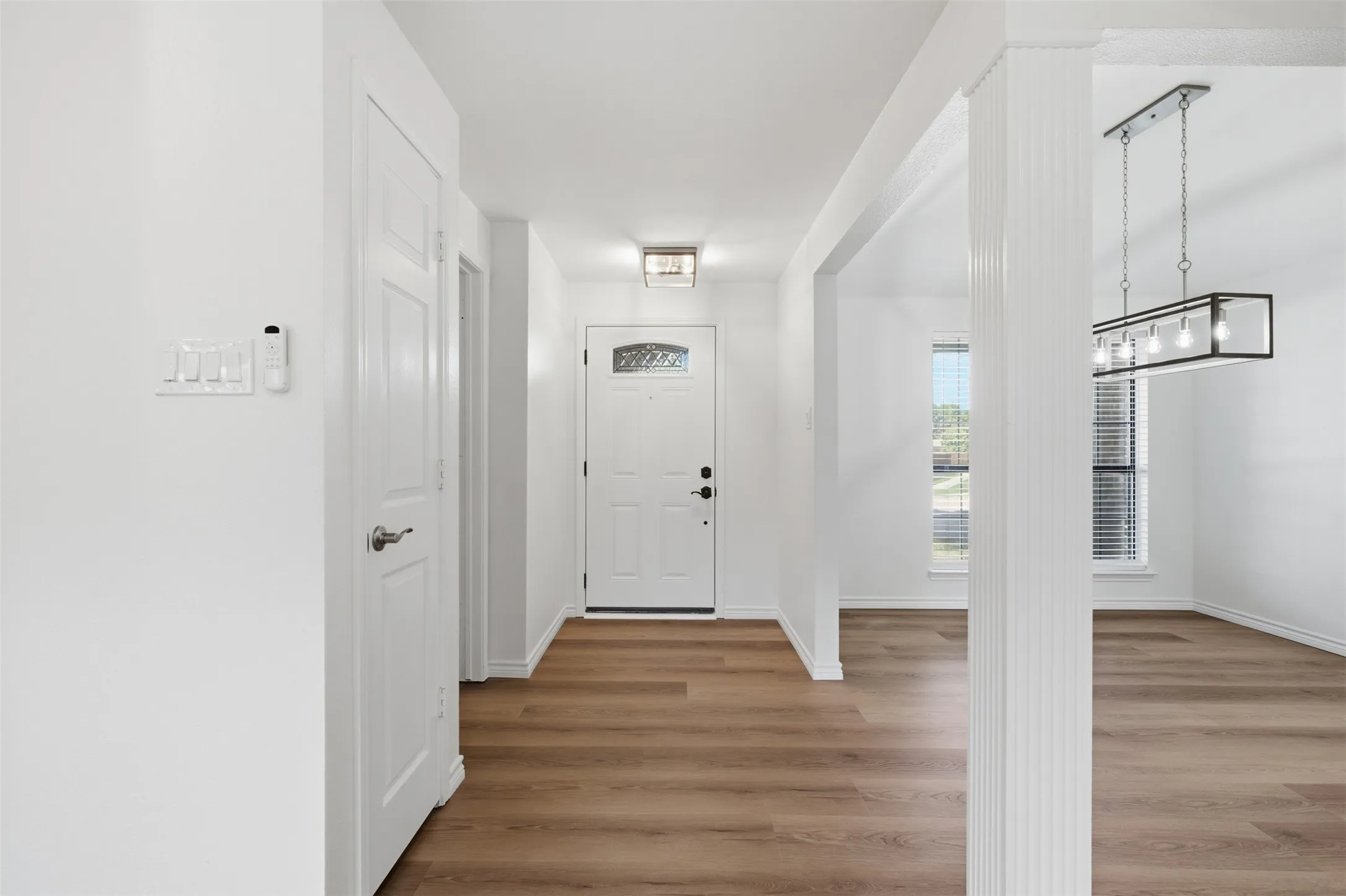 Wood-finish flooring throughout, white interior doors, and a decorative front entry door with a clear glass insert