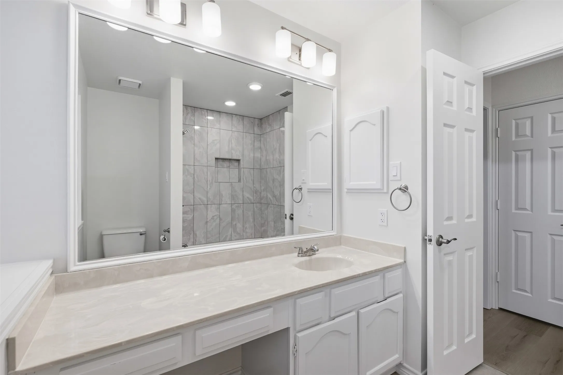Expansive vanity featuring a single basin, light-toned countertop, and white cabinetry