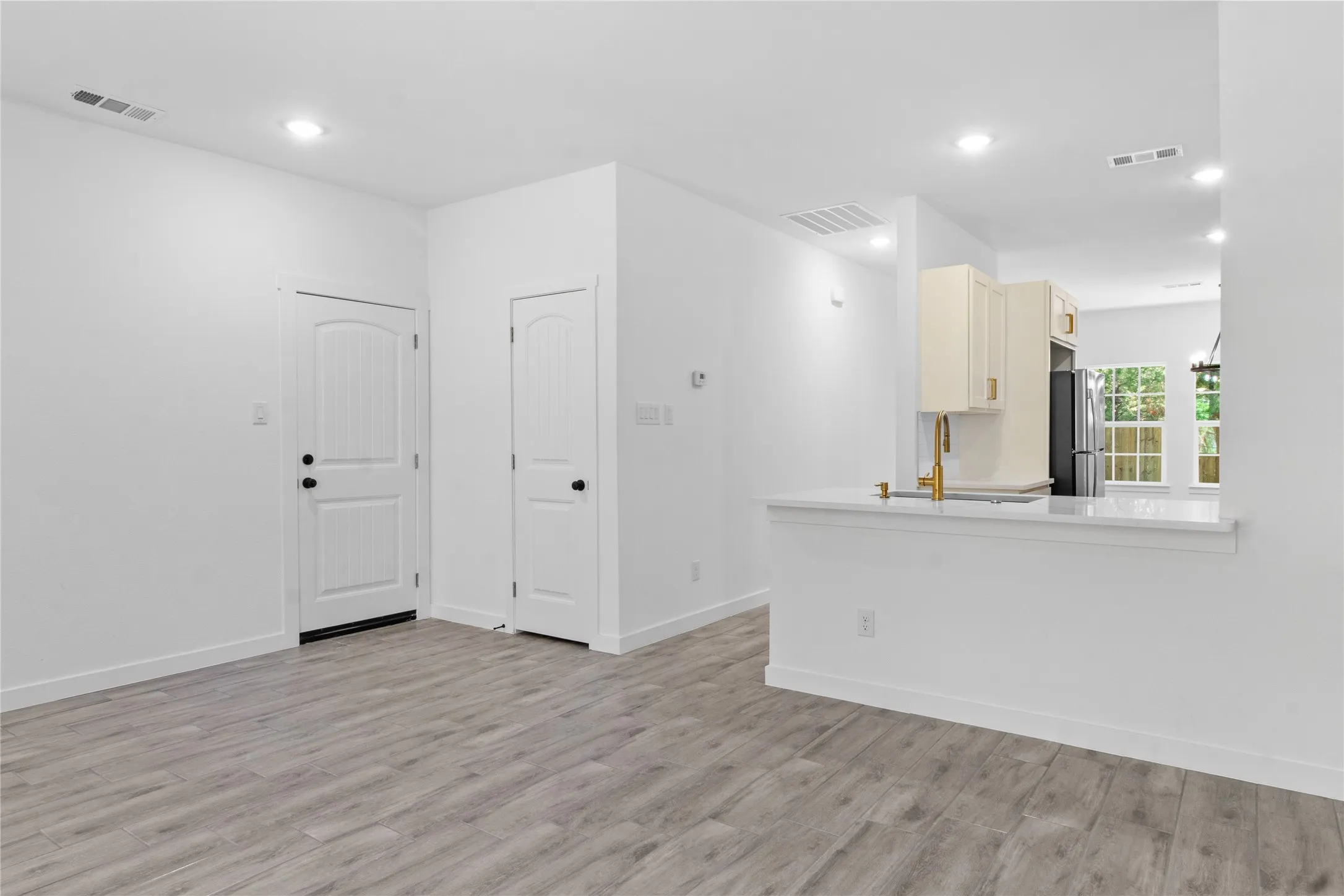 Open-concept design featuring wood-finish flooring, recessed lighting, and a kitchen pass-through with a light-toned countertop