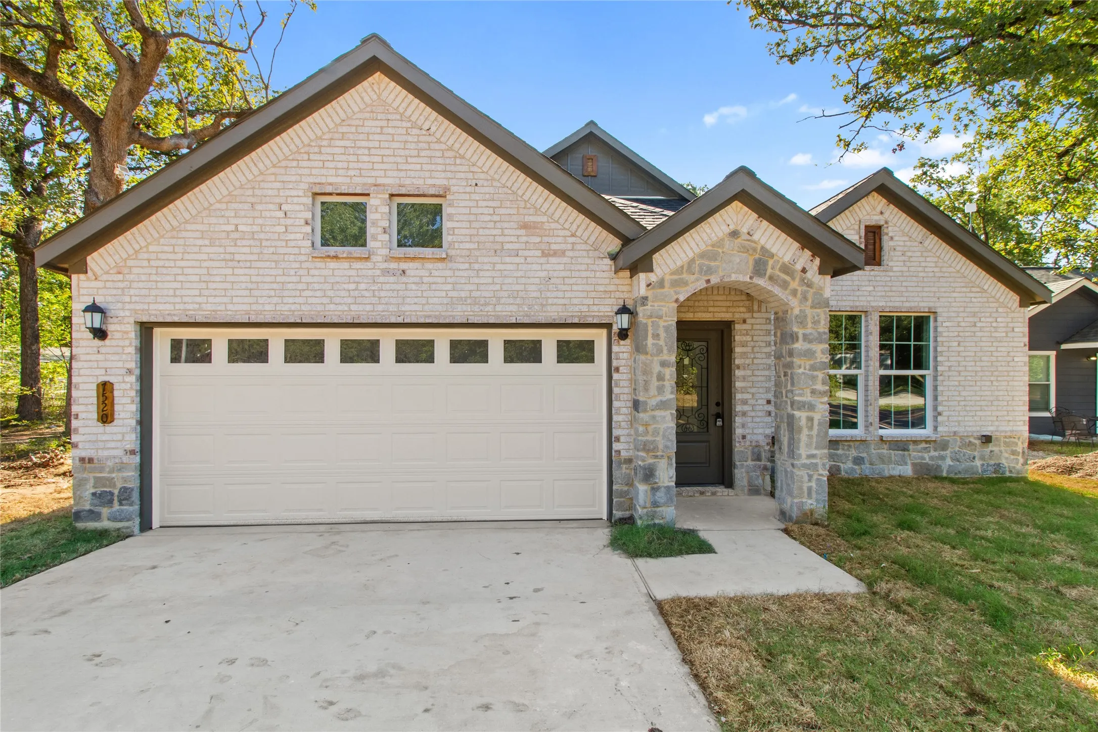 Brick and stone exterior with a covered entry, attached garage, and multiple gables
