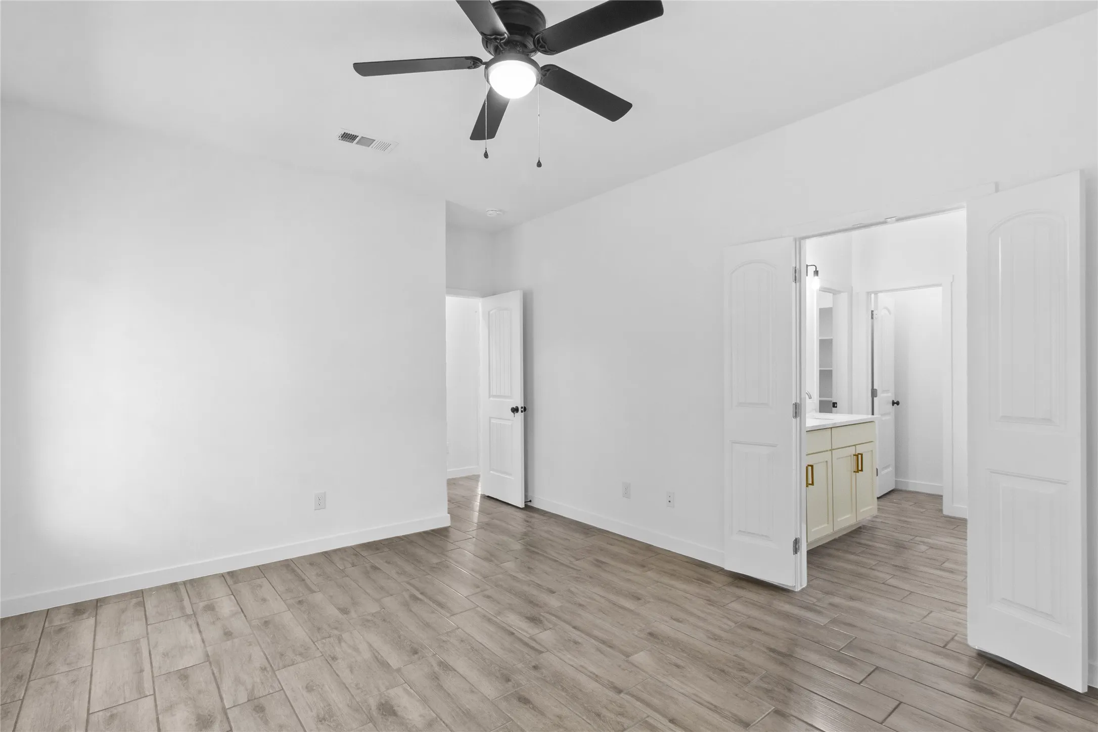 Spacious room with wood-finish flooring and a ceiling fan