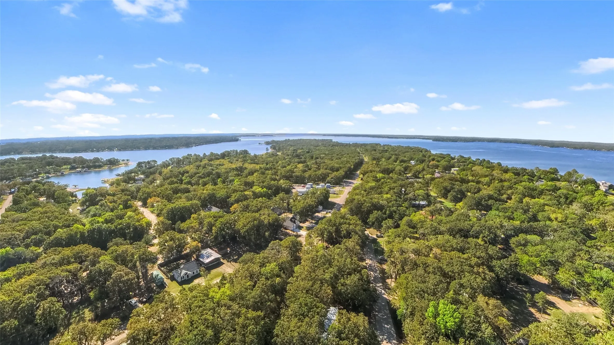Expansive water frontage with mature tree canopy and scattered residential structures