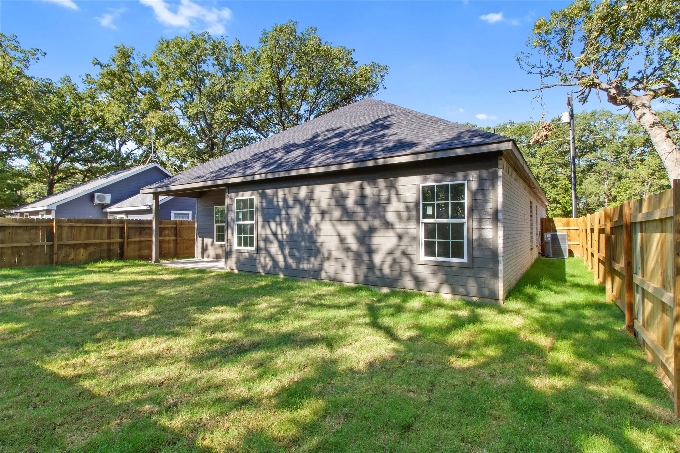 Charming single-story residence with a gable roof and board-and-batten siding, situated on a spacious lot with mature shade trees