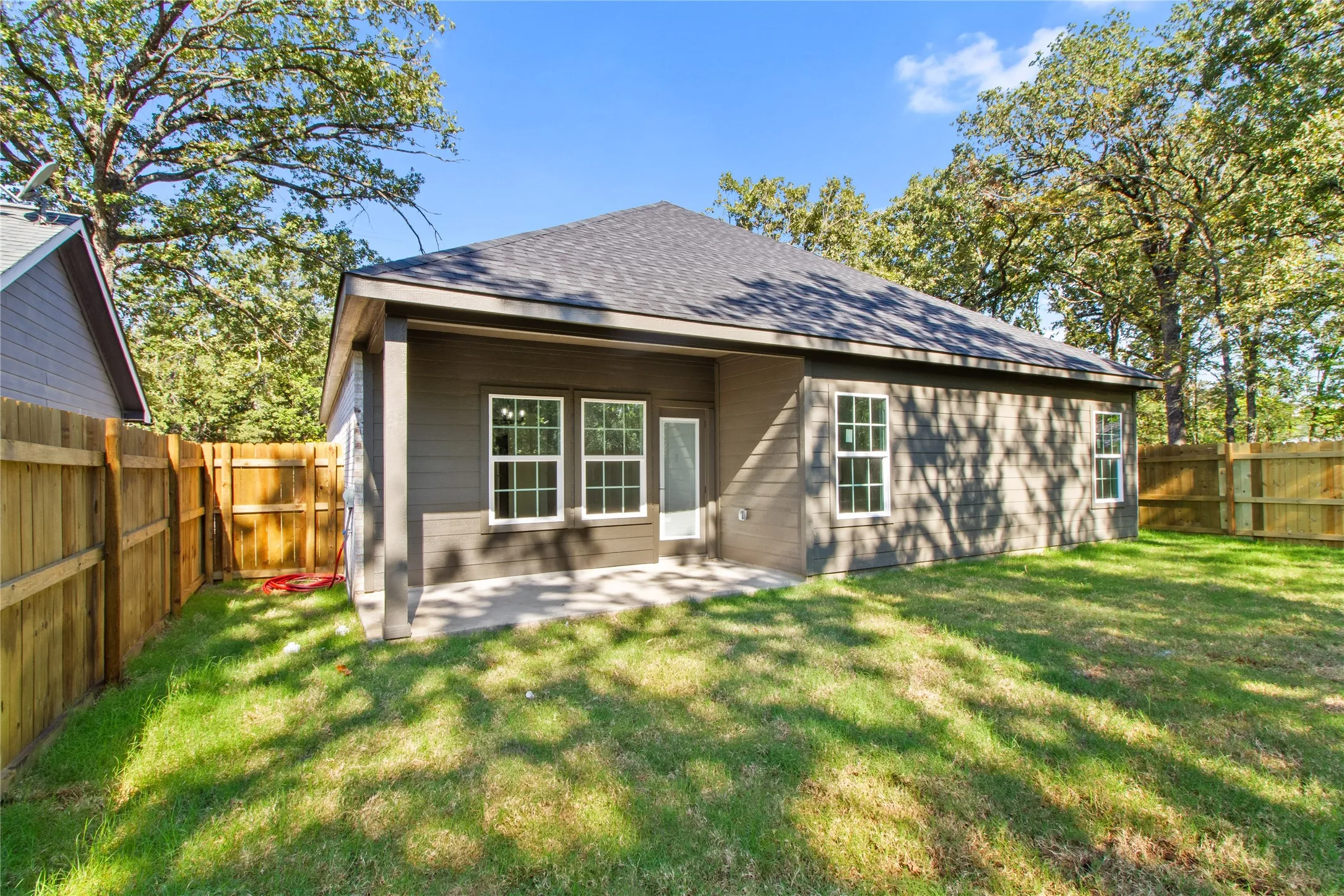 Backyard featuring a covered patio, multiple windows, and wood fencing