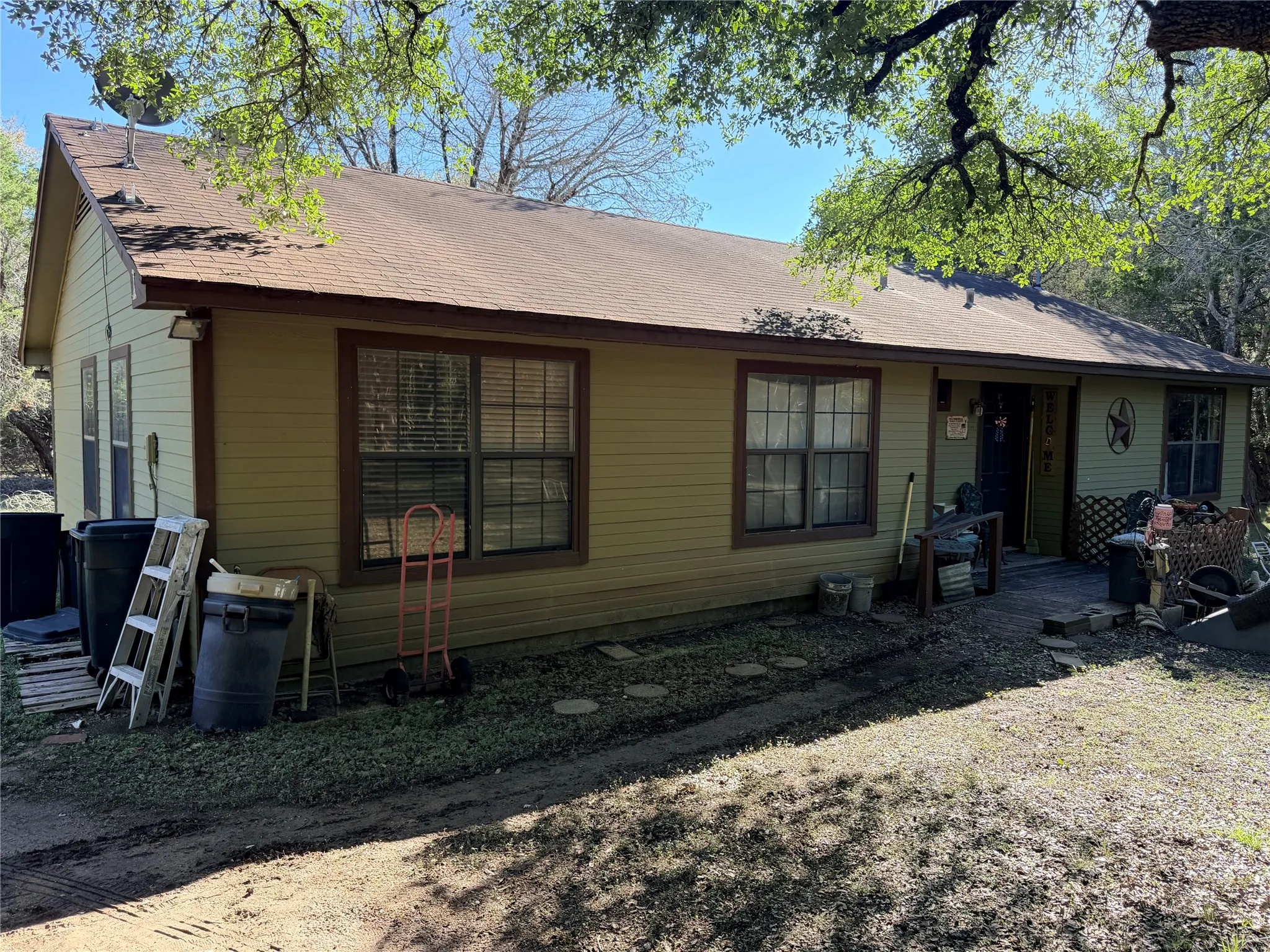 Charming single-story home featuring horizontal siding exterior, multiple large windows with dark frames, and a covered front porch