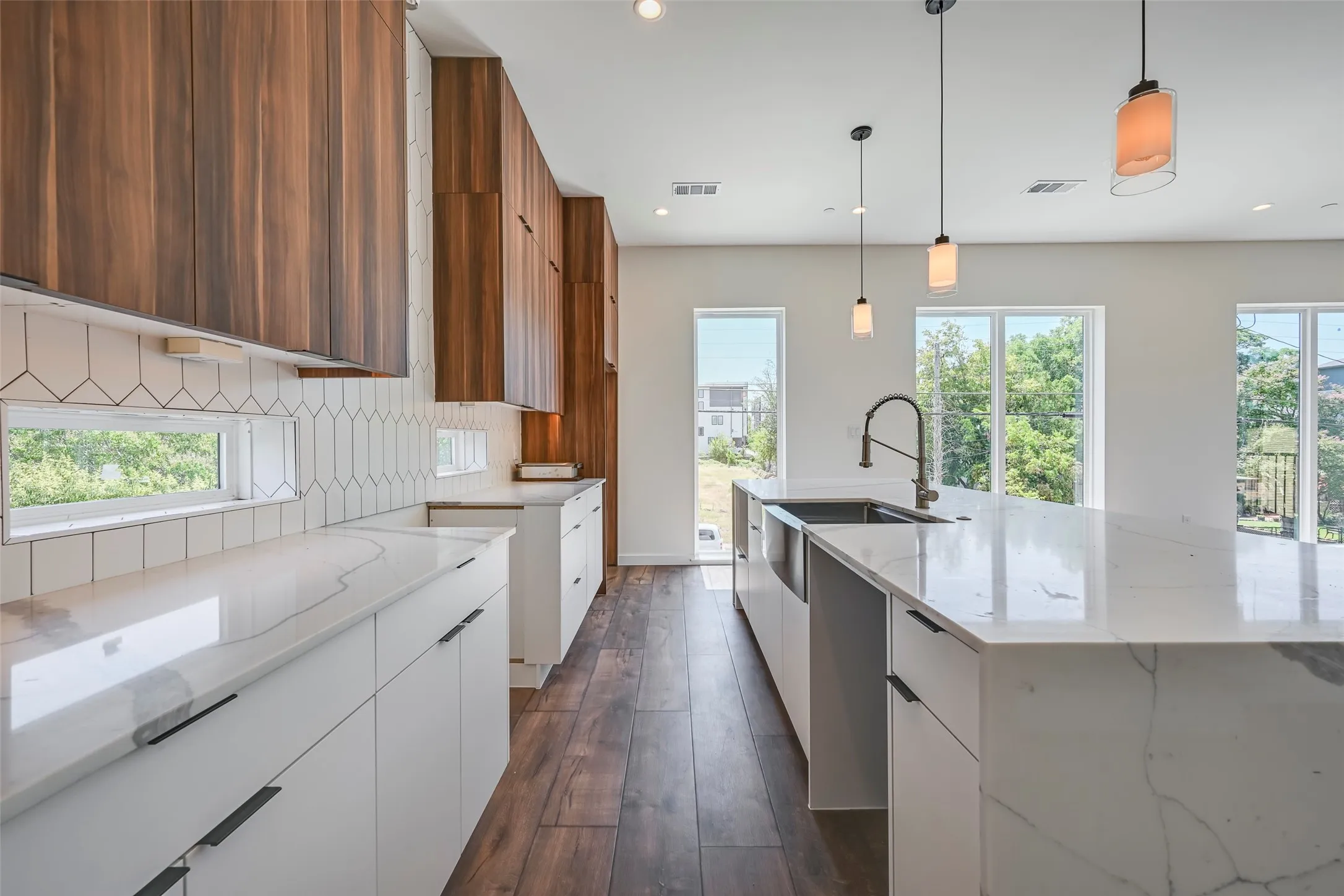Kitchen featuring wood-finish upper cabinetry, white lower cabinetry, white countertops, a tiled backsplash, and wood-finish flooring