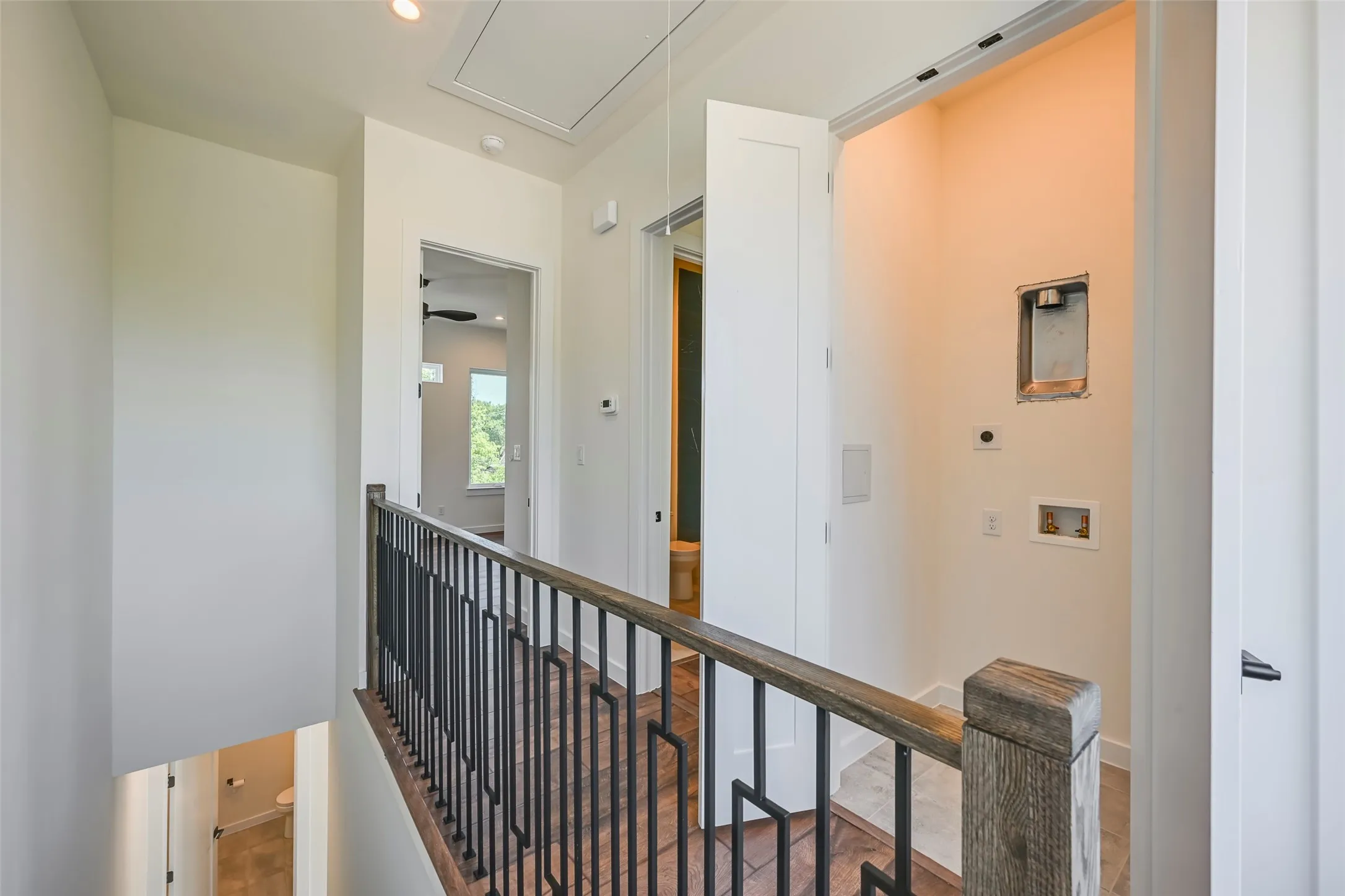 Wood-finish flooring, metal railing with geometric design, and recessed lighting