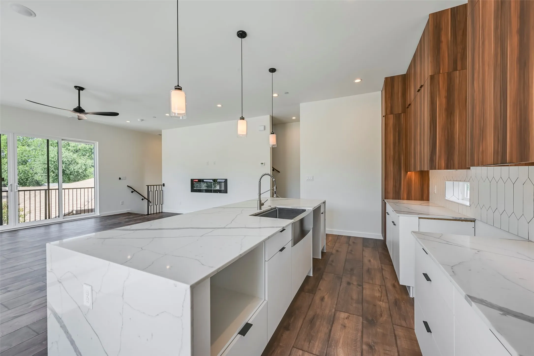 Expansive kitchen island with a waterfall countertop, integrated sink, and pendant lighting