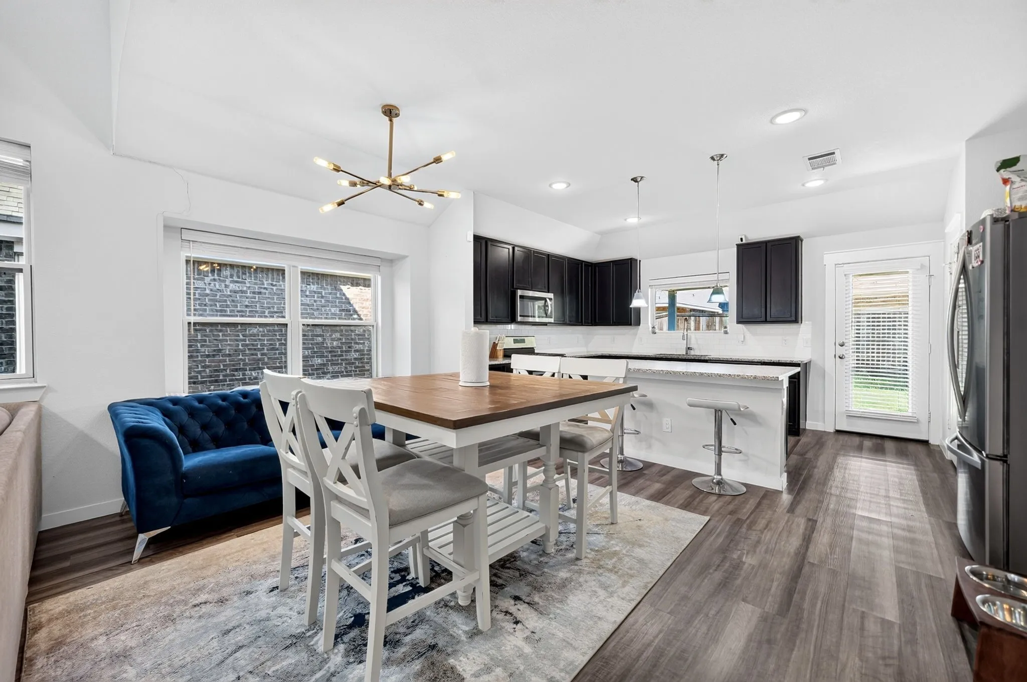 Open-concept living space with wood-finish flooring, a contemporary chandelier, and recessed lighting