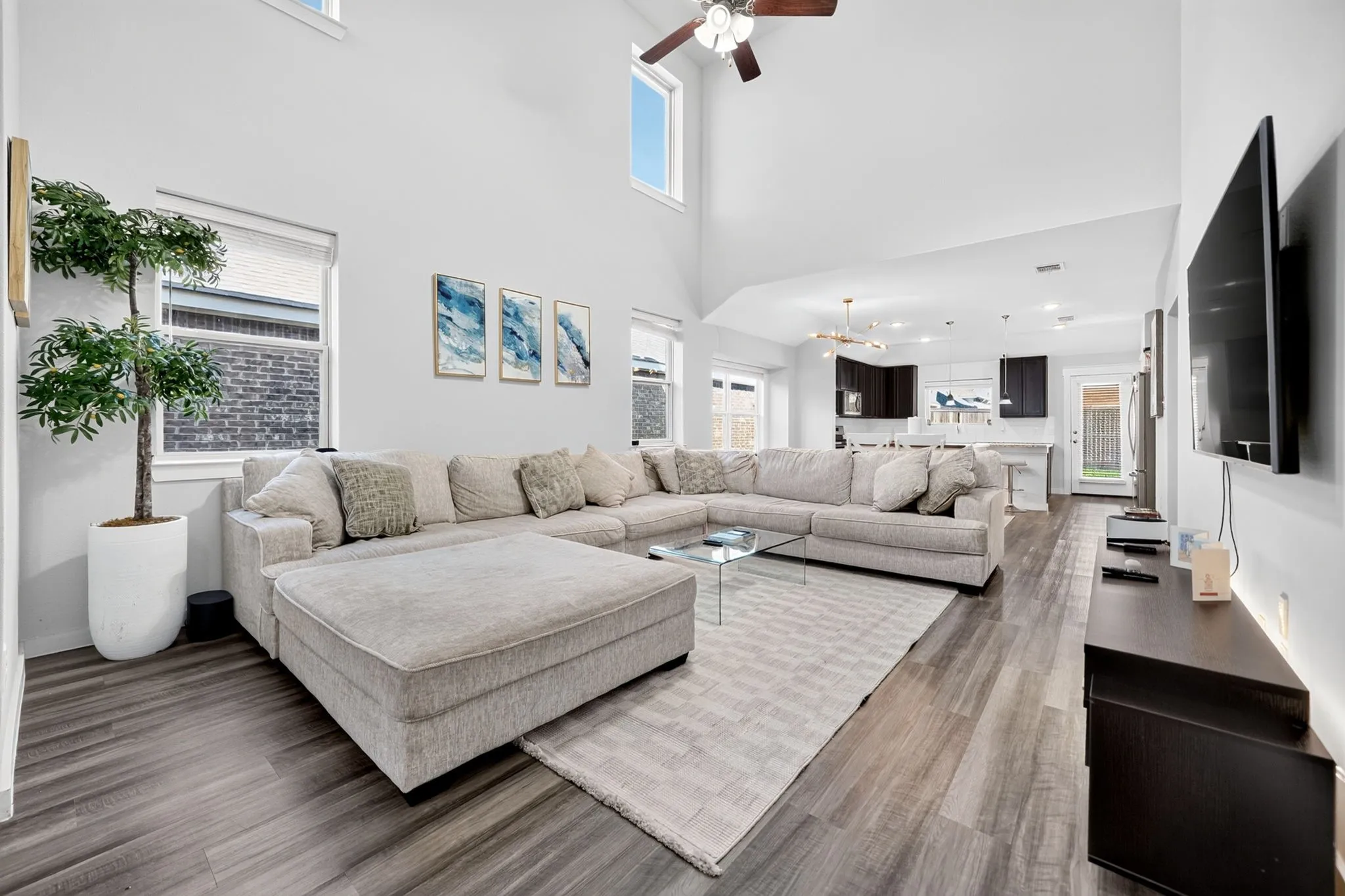 Vaulted ceiling with a ceiling fan, elevated windows, wood-finish flooring, and an open-concept layout