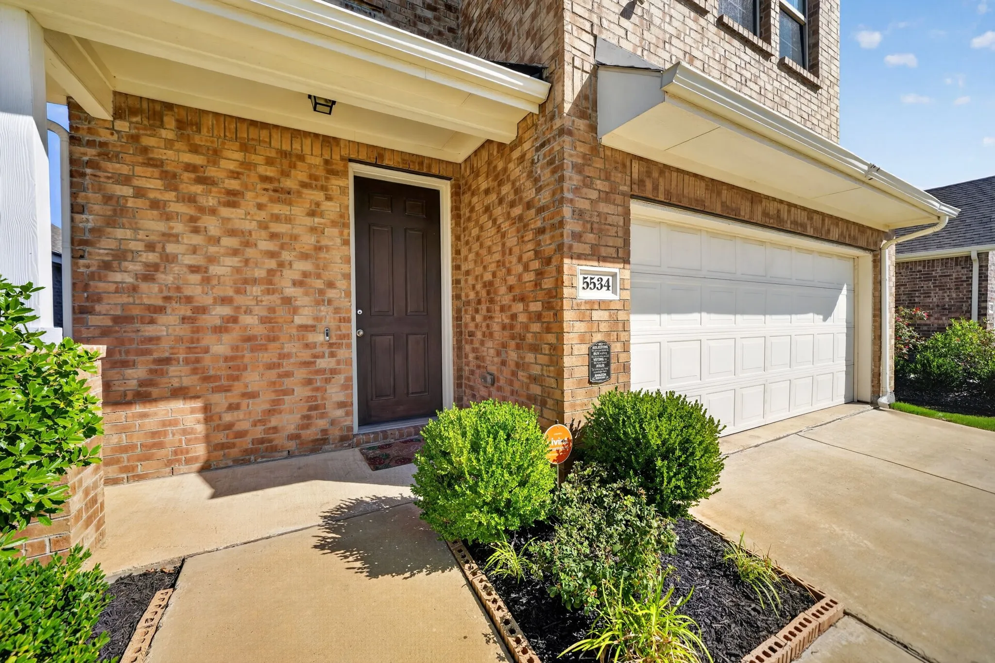 Welcoming brick front elevation with a covered entry featuring a dark wood door and sidelights