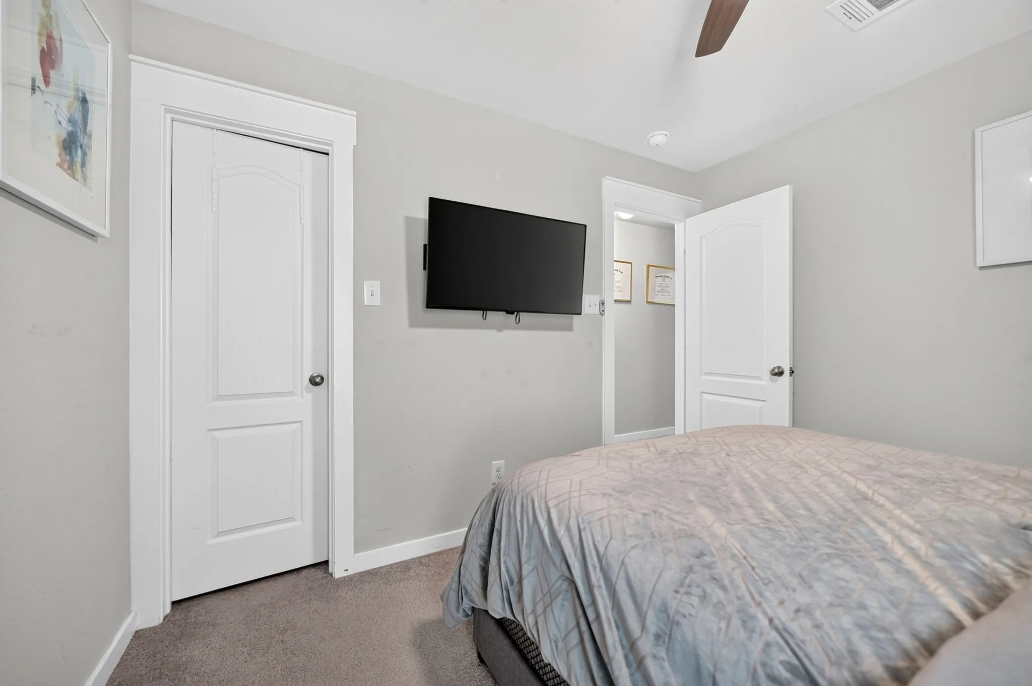 Spacious secondary bedroom with neutral wall finishes, carpet flooring, and dual closet doors providing ample storage