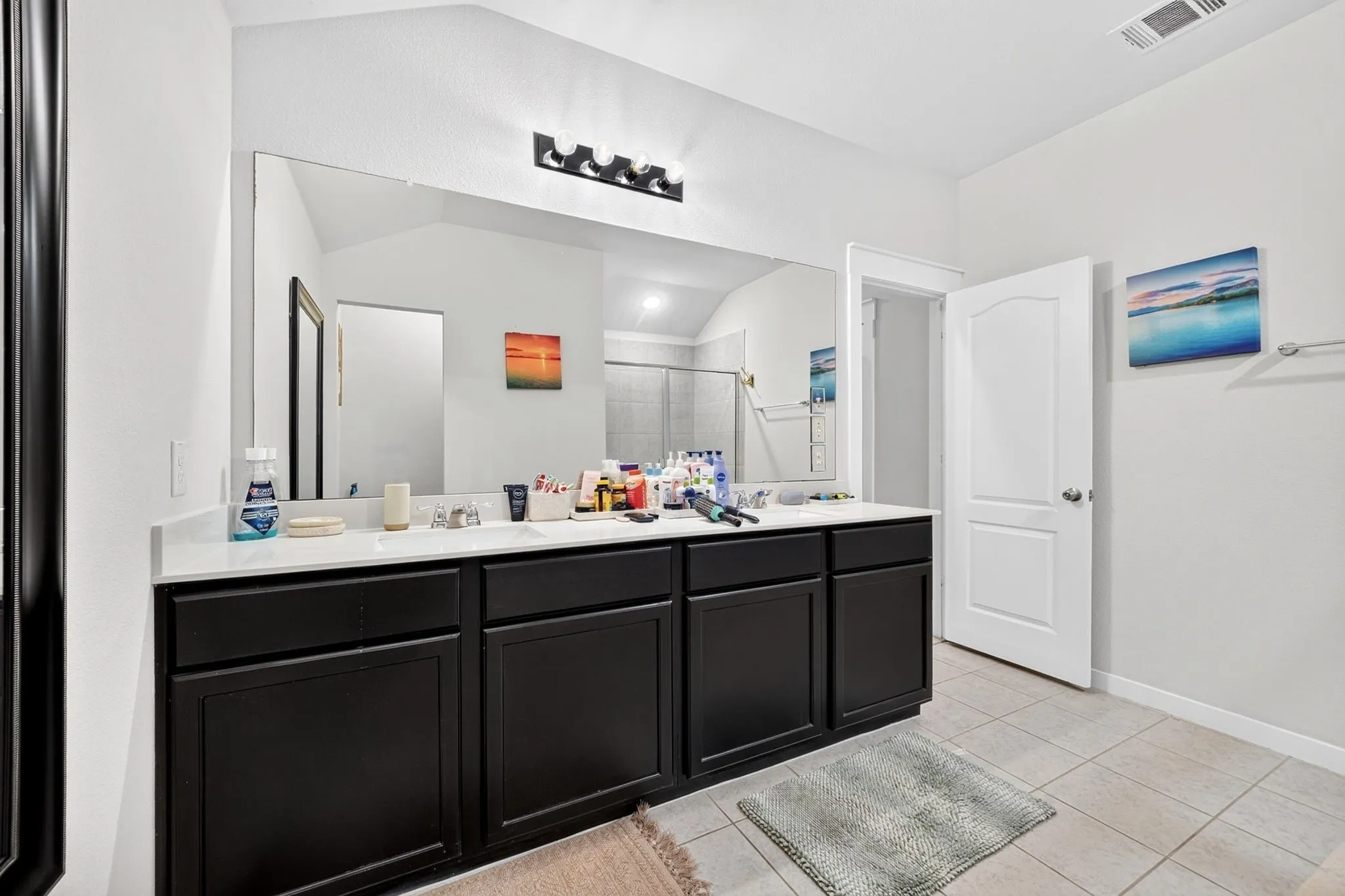 Dual vanity with white countertop, dark wood-finish cabinetry, and a large wall-mounted mirror