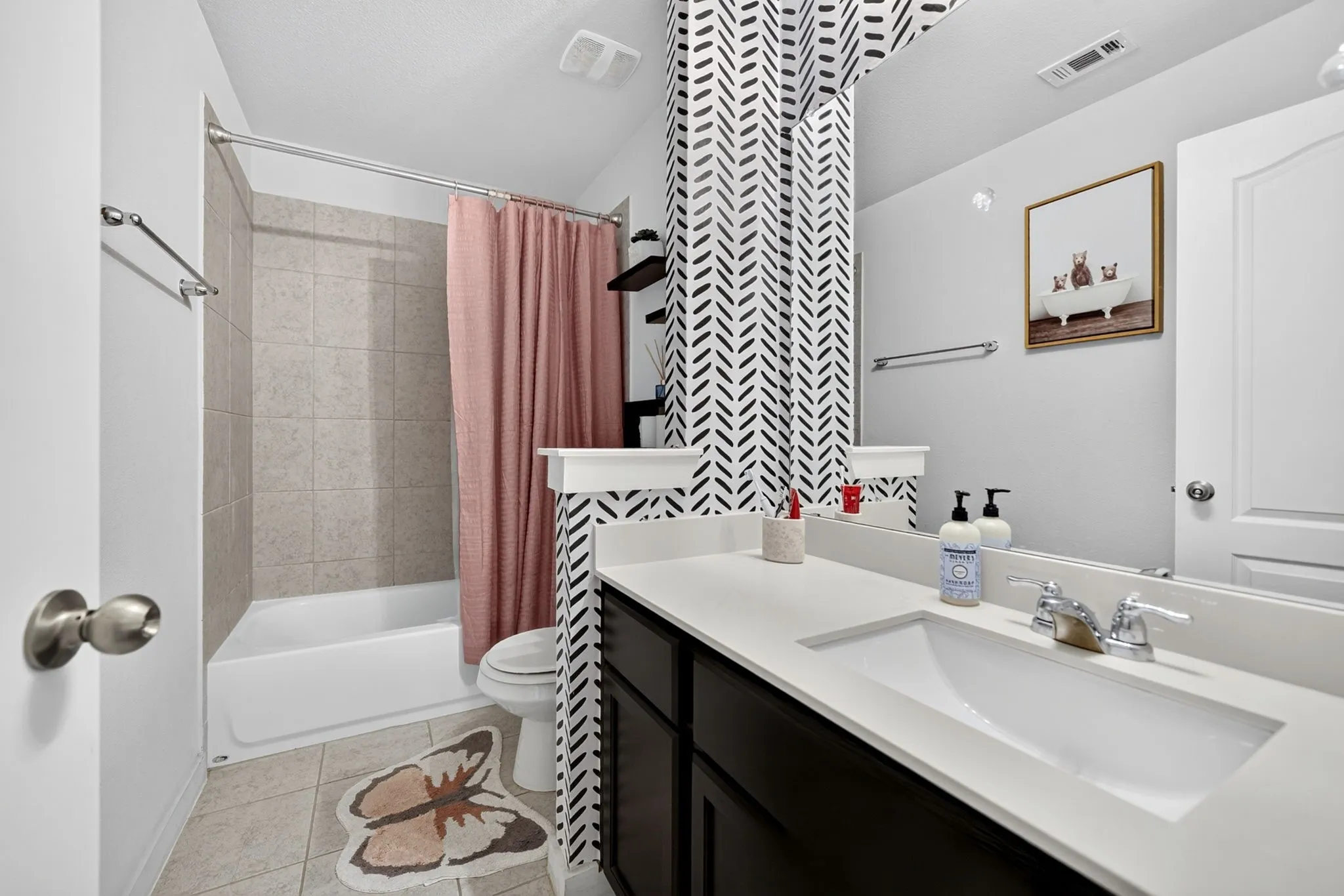 Bathroom featuring a vanity with an integrated sink, polished chrome faucet, full-width mirror, and a tiled tub/shower combination