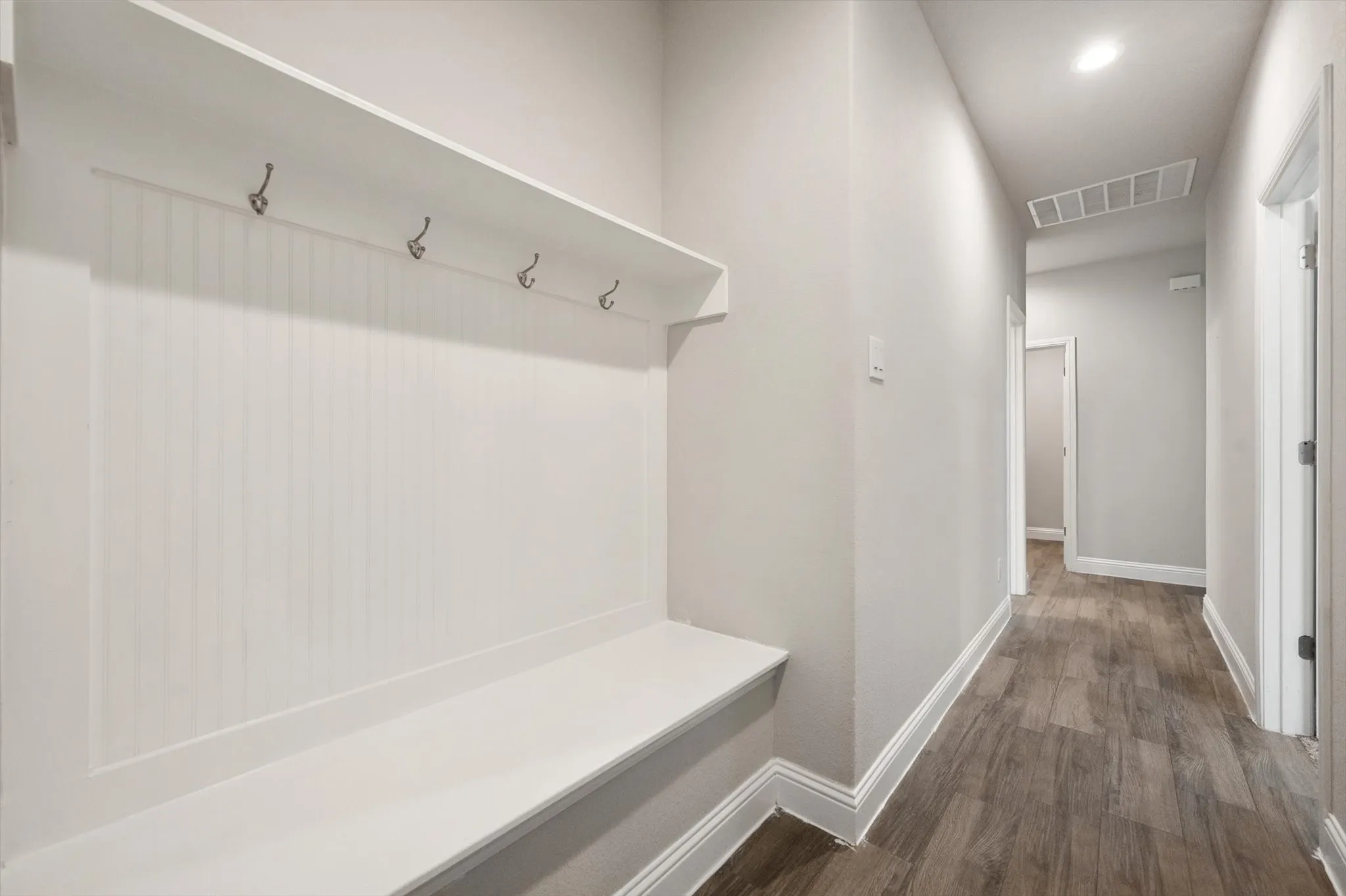 Built-in hall tree with bench and storage shelf, featuring metal hooks and beadboard detailing