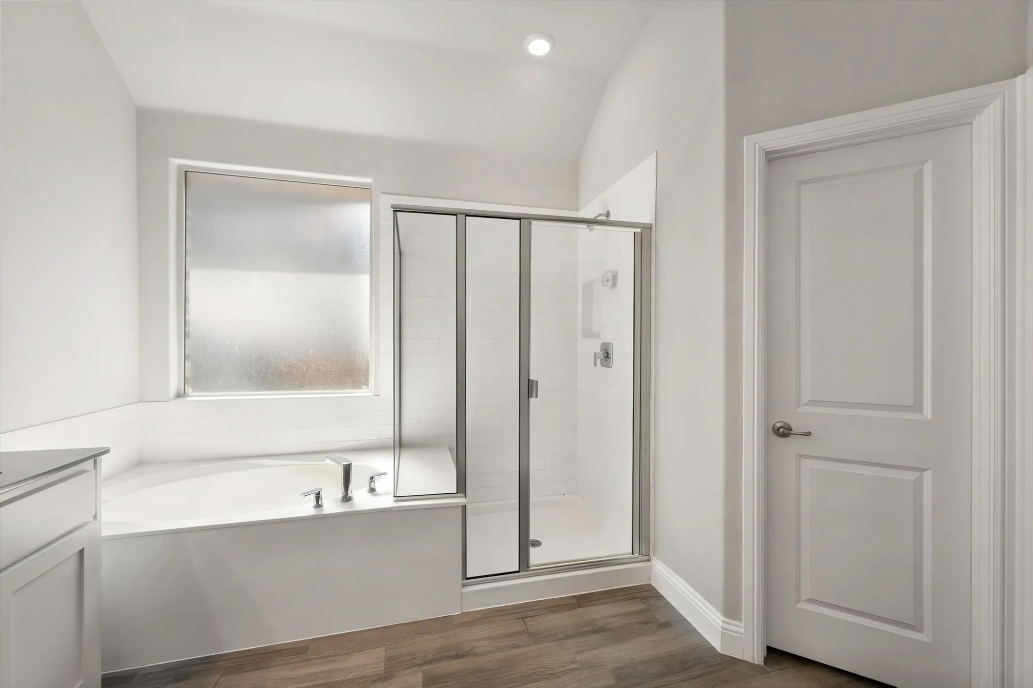 Soaking tub with deck-mounted fixtures, glass-enclosed shower with tile surround