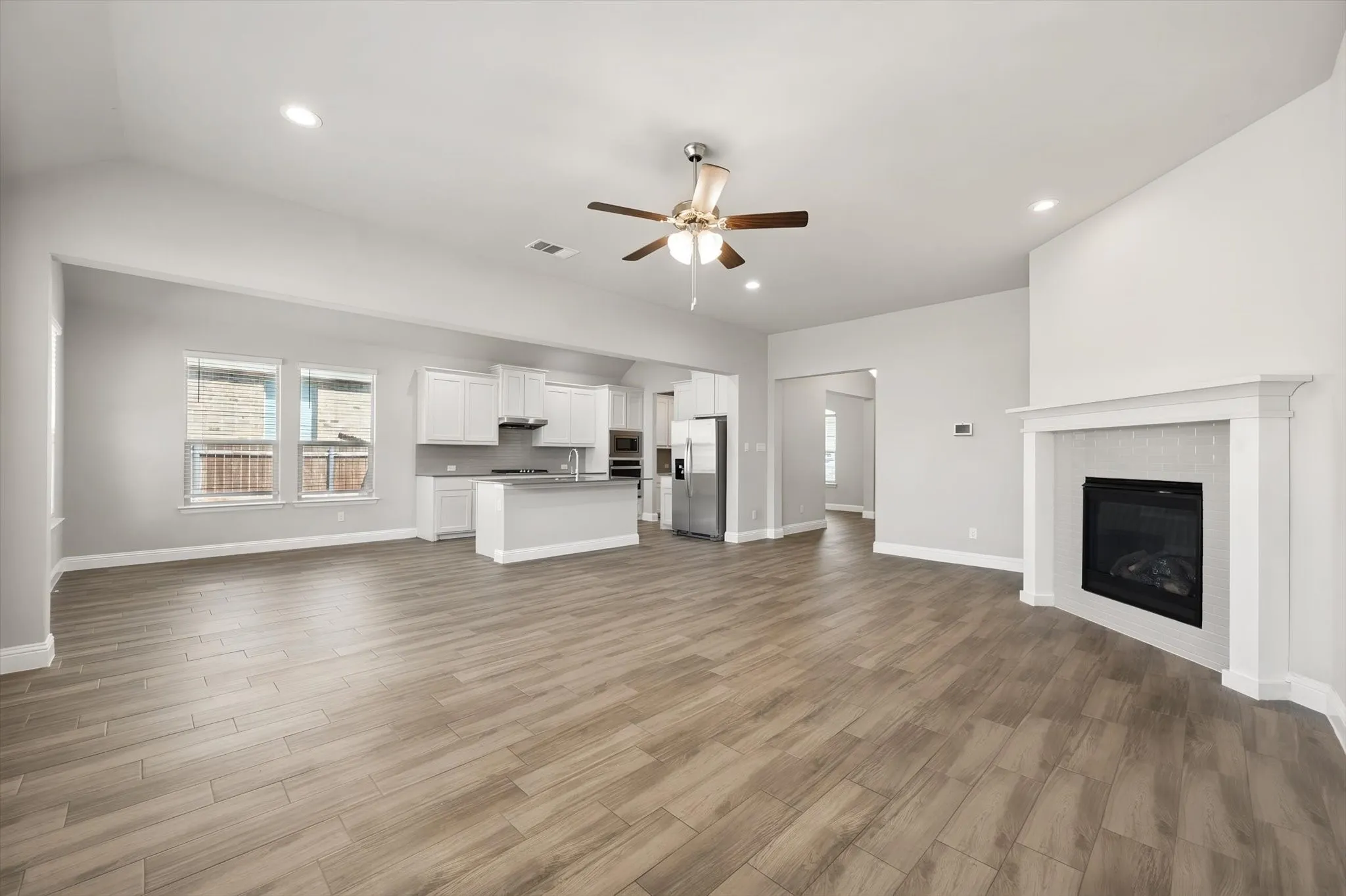 Open-concept living space a contemporary fireplace with tile surround, and recessed lighting