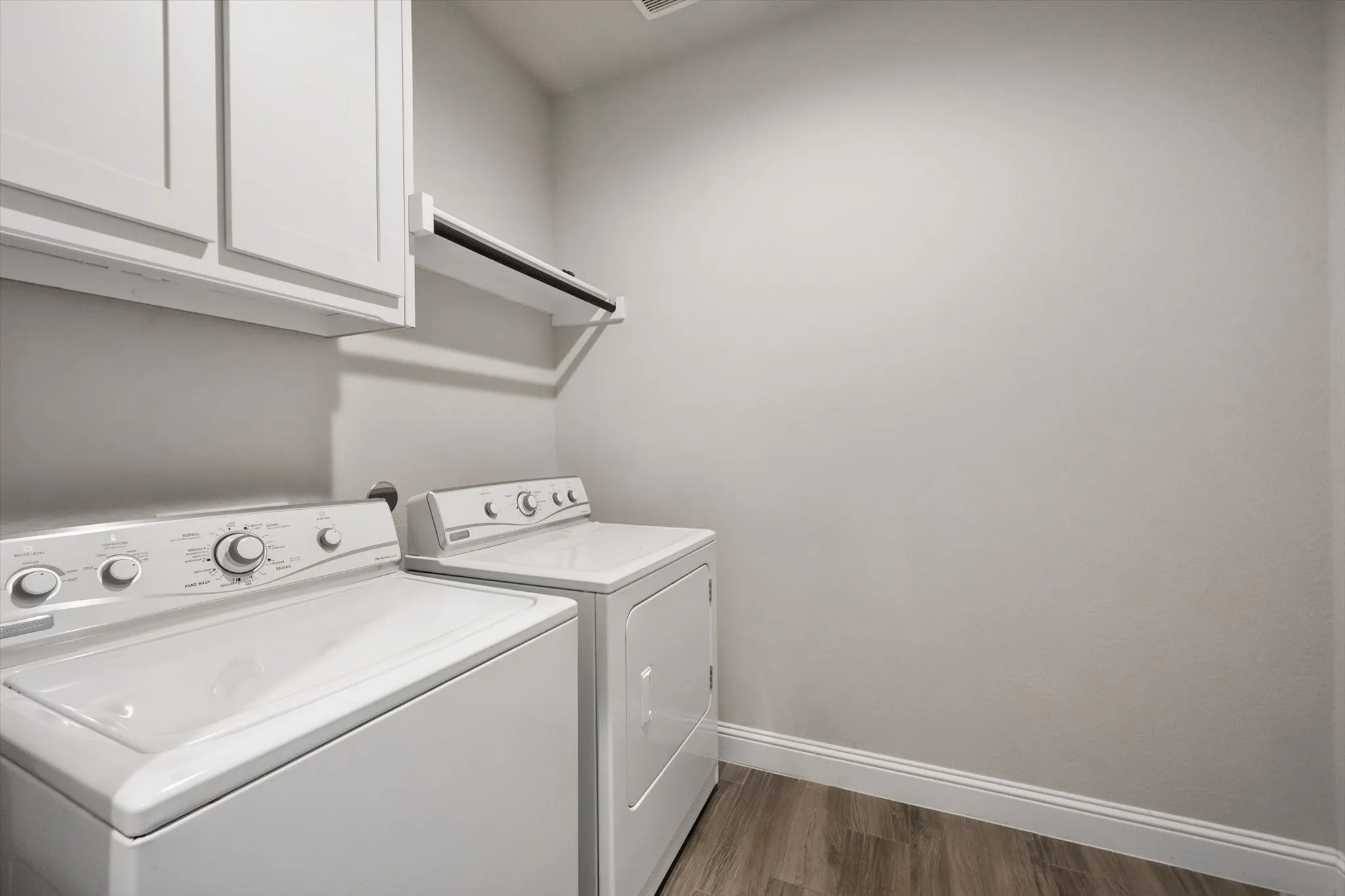 Dedicated laundry room featuring side-by-side front-load washer and dryer, white cabinetry and ample counter space for folding and sorting. Washer and dryer stay with the home.