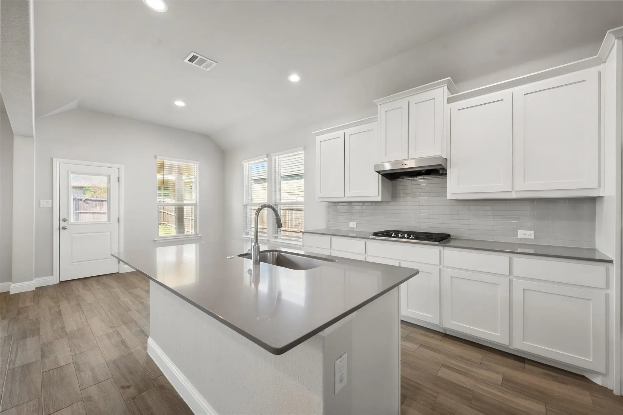 Kitchen featuring white cabinetry, grey countertops, stainless steel range hood and recessed lighting