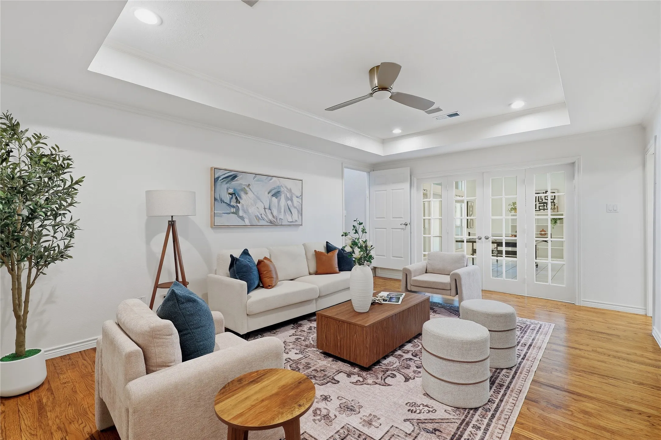 Living area featuring a tray ceiling, recessed lighting, a ceiling fan, wood-finish flooring, and double French doors