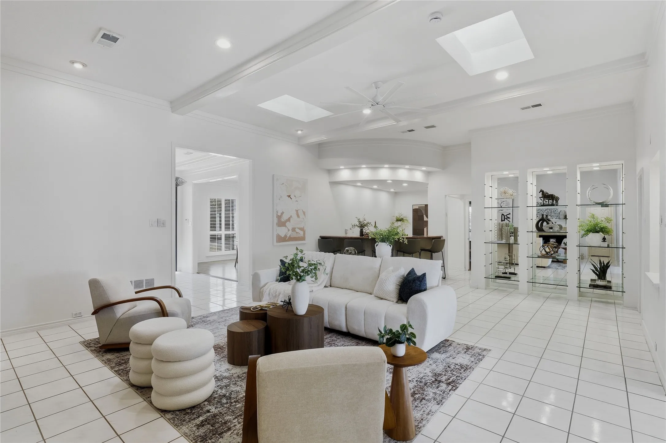 Spacious living area featuring tile flooring, skylights, recessed lighting, and crown molding