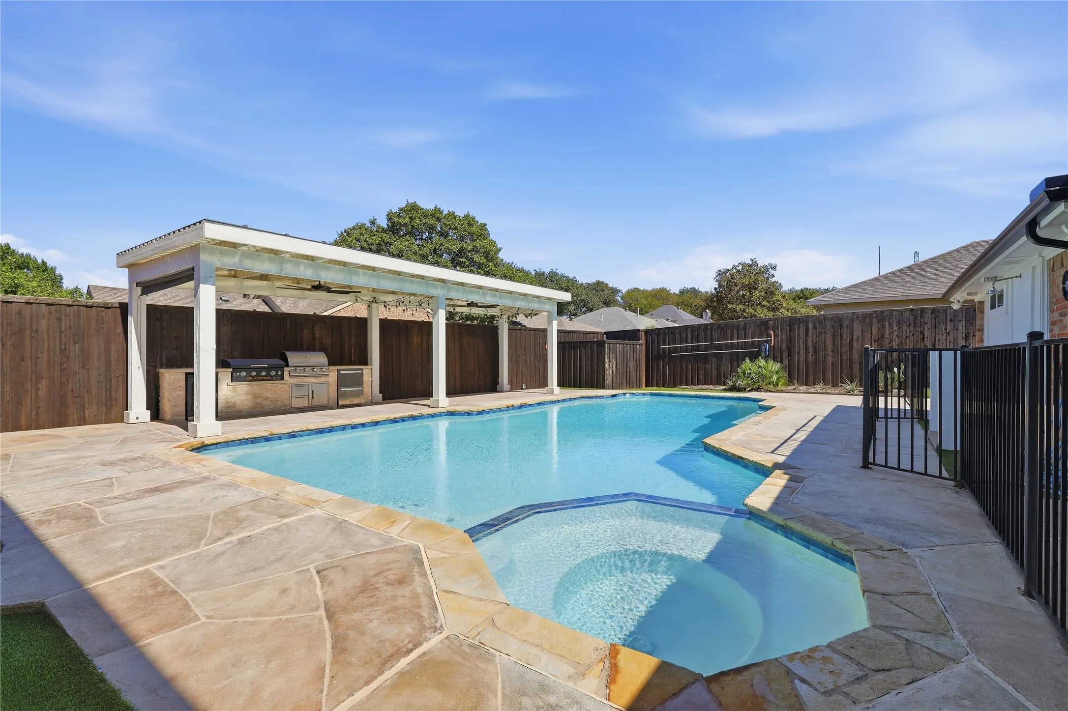 Swimming pool with integrated spa, flagstone coping, and surrounding patio