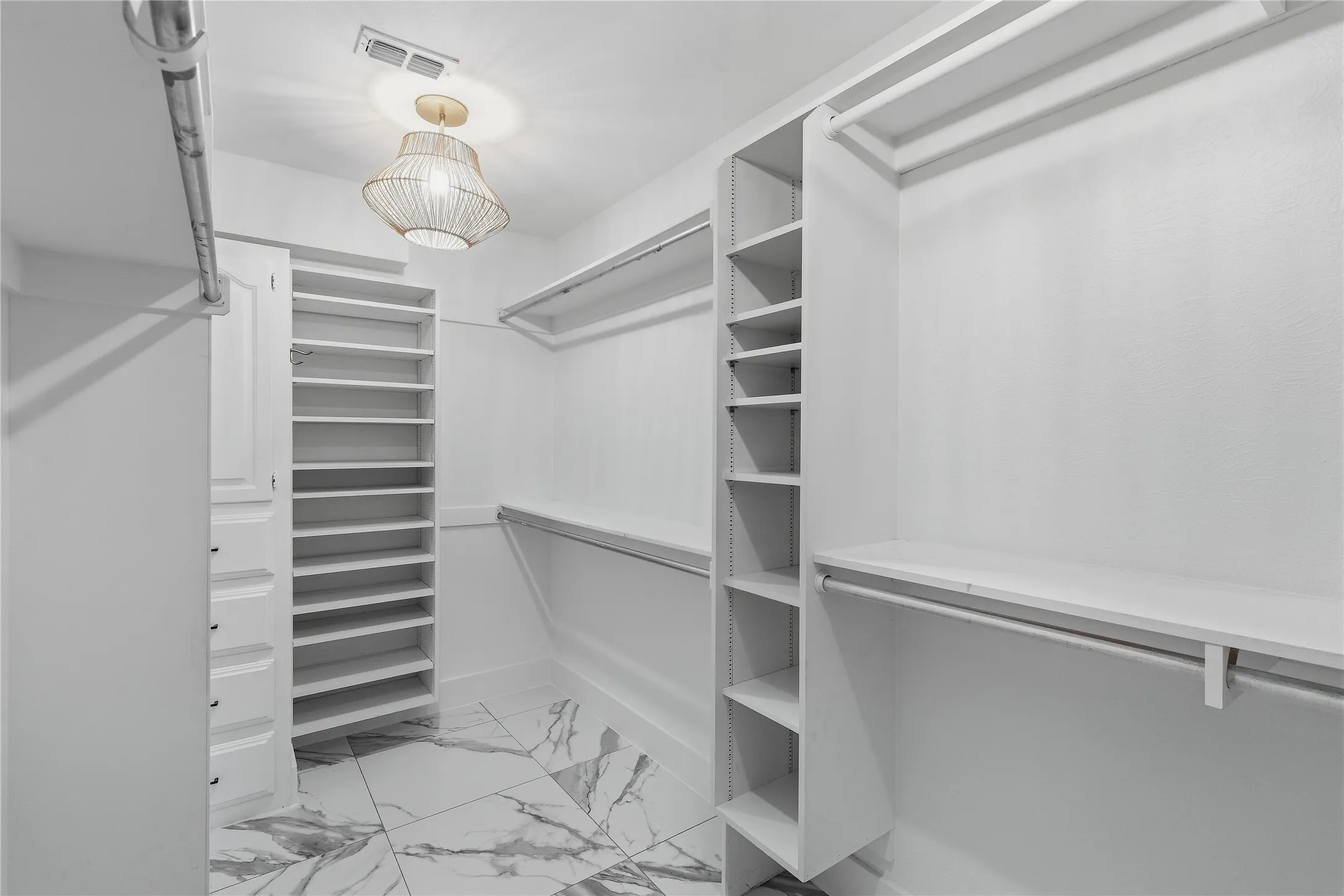 White custom closet system with hanging rods, integrated shelving units, and a built-in drawer cabinet