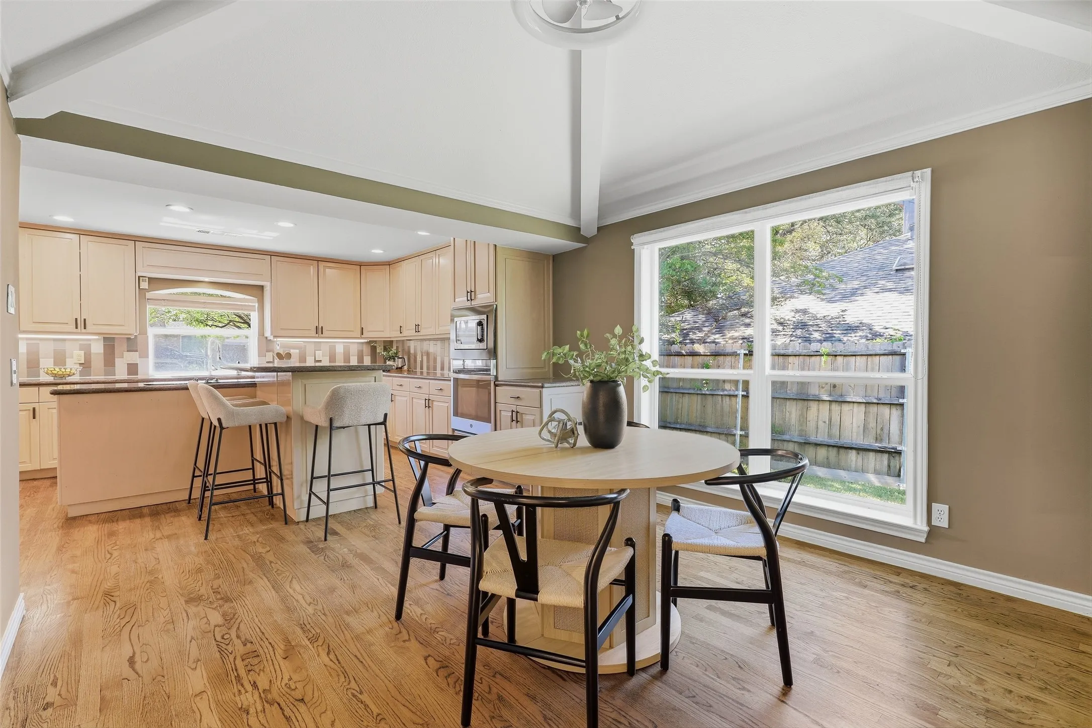 Gourmet kitchen with light wood-finish cabinetry, built-in appliances, and a central island with bar seating